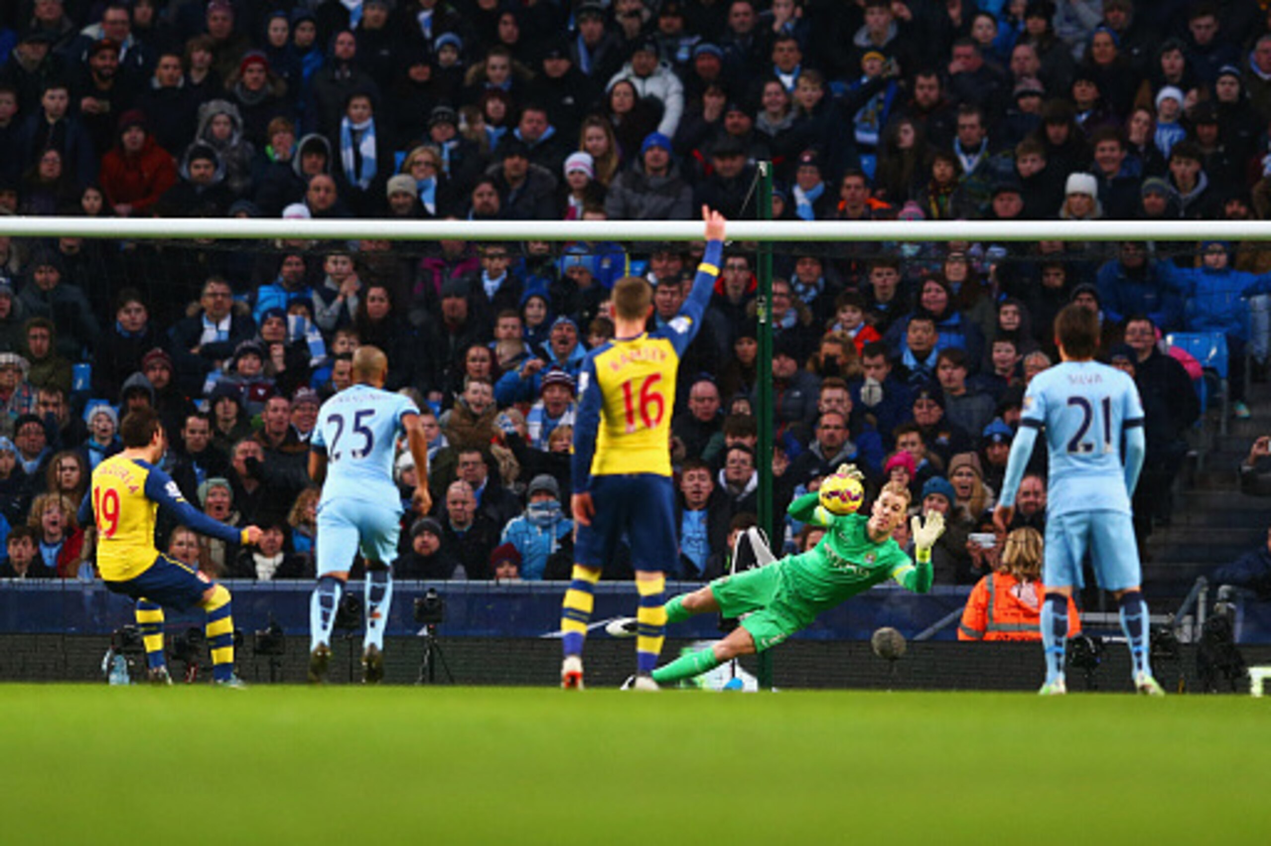 MANCHESTER, ENGLAND - JANUARY 18:  Santi Cazorla of Arsenal (19) shoots past goalkeeper Joe Hart of Manchester City to score their first goal from a penalty during the Barclays Premier League match between Manchester City and Arsenal at Etihad Stadium on 