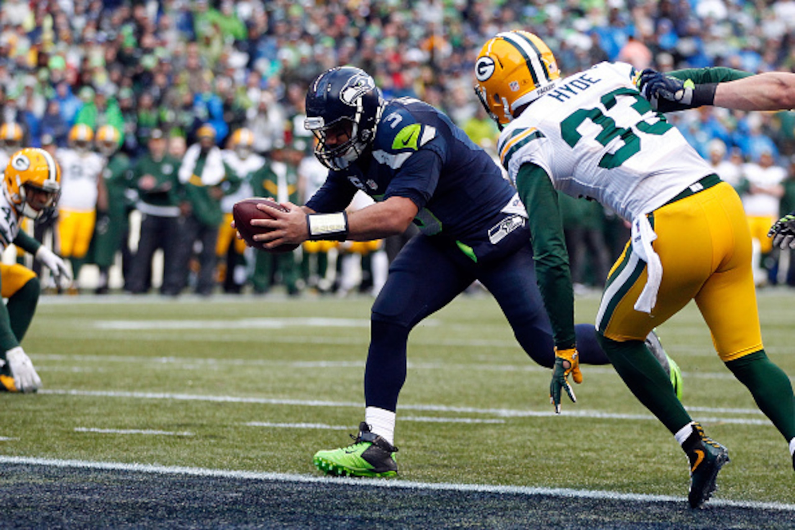 SEATTLE, WA - JANUARY 18:  Russell Wilson #3 of the Seattle Seahawks runs the ball in for a touchdown as  Micah Hyde #33 of the Green Bay Packers closes in during the fourth quarter of the 2015 NFC Championship game at CenturyLink Field on January 18, 201