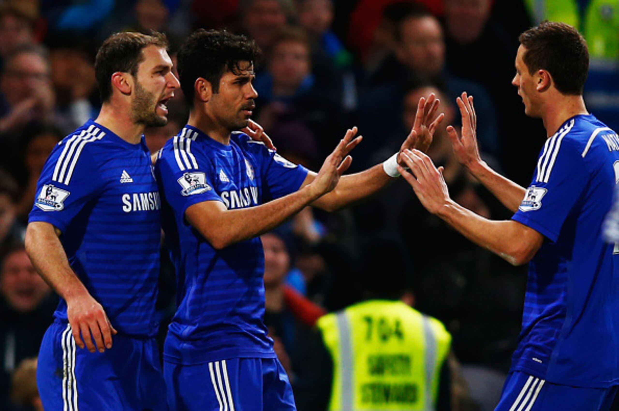 LONDON, ENGLAND - DECEMBER 13:  Diego Costa of Chelsea (C) celebrates with team mates Branislav Ivanovic (L) and Nemanja Matic (R) as he scores their second goal during the Barclays Premier League match between Chelsea and Hull City at Stamford Bridge on 