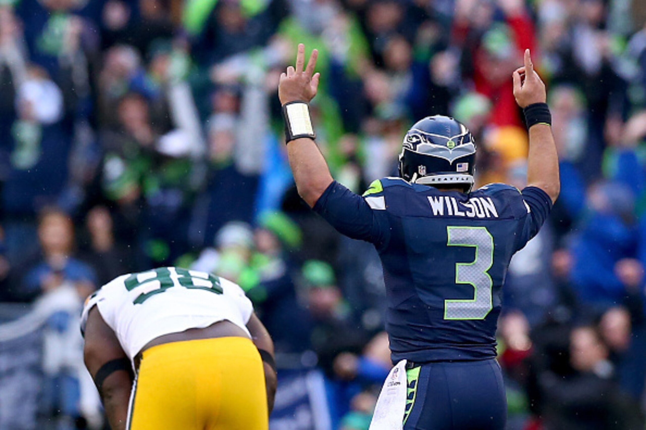 SEATTLE, WA - JANUARY 18: Russell Wilson #3 of the Seattle Seahawks celebrates as Letroy Guion #98 of the Green Bay Packers is in anguish after Wilson threw a game winning touchdown pass in overtime of the 2015 NFC Championship game at CenturyLink Field o