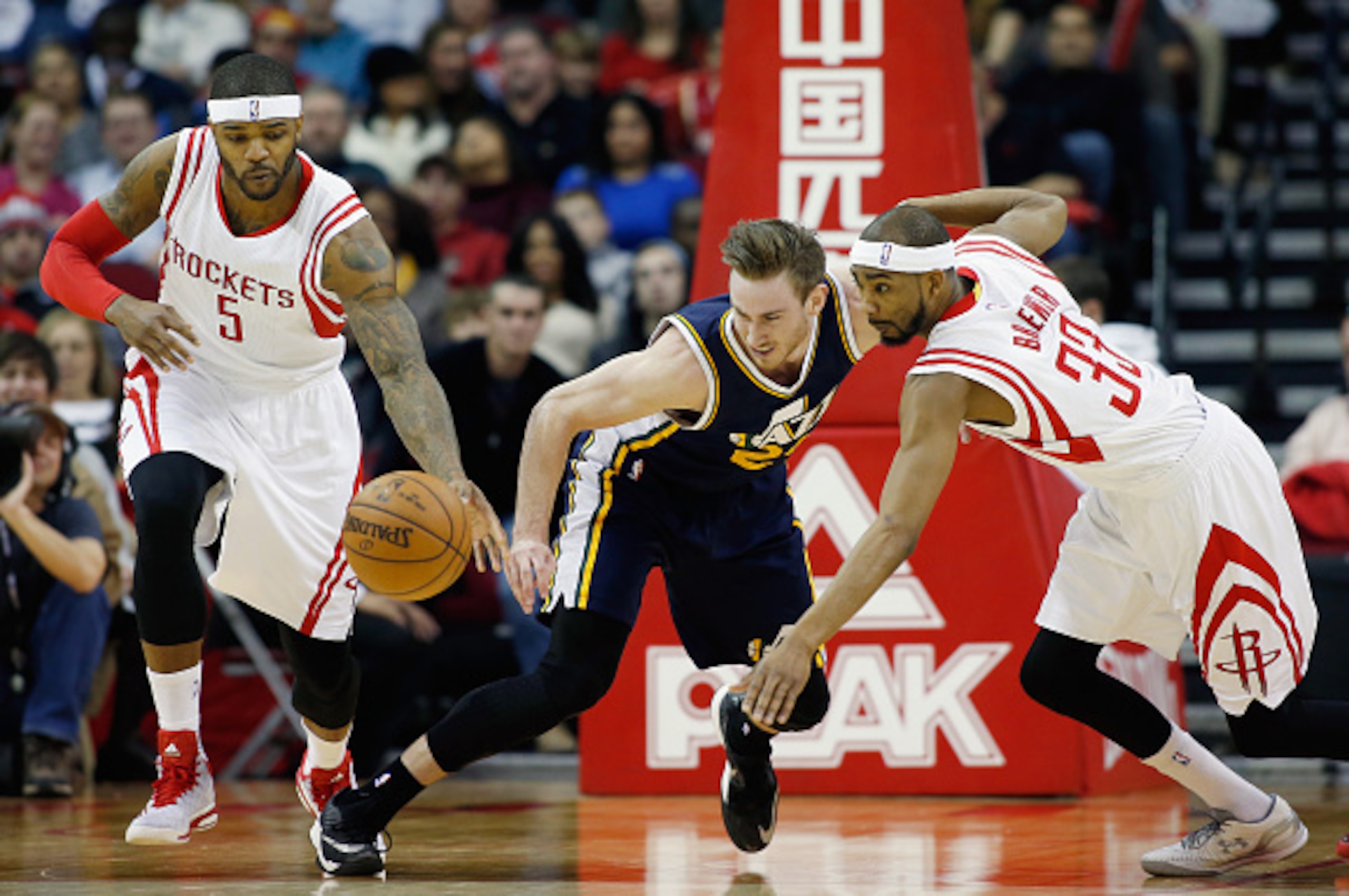 HOUSTON, TX - JANUARY 10:  Gordon Hayward #20 of the Utah Jazz reaches for the basketball in front of Josh Smith and Corey Brewer #33 of the Houston Rockets during their game at the Toyota Center on January 10, 2015 in Houston, Texas.  NOTE TO USER: User 