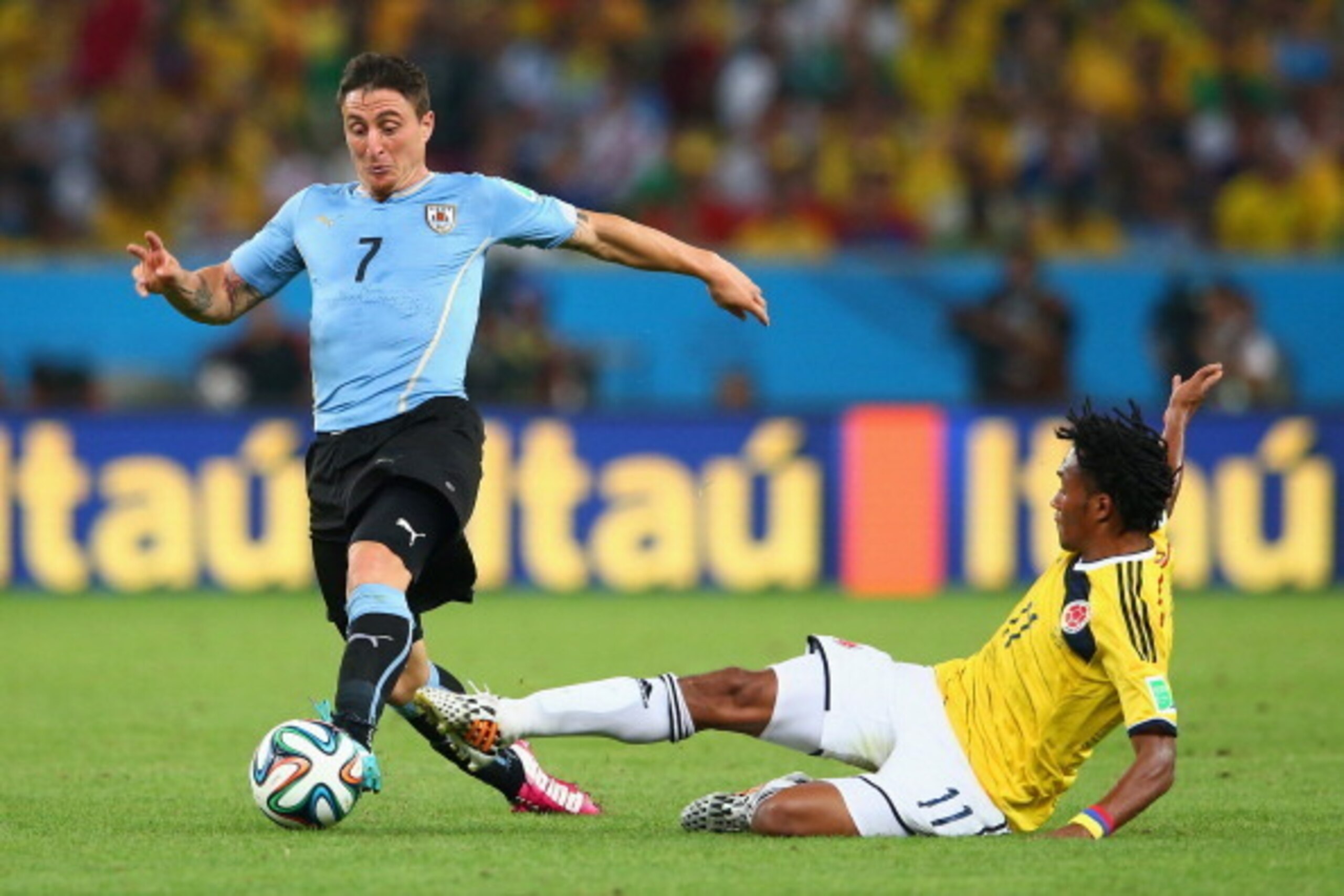 RIO DE JANEIRO, BRAZIL - JUNE 28:  Juan Guillermo Cuadrado of Colombia tackles Cristian Rodriguez of Uruguay during the 2014 FIFA World Cup Brazil round of 16 match between Colombia and Uruguay at Maracana on June 28, 2014 in Rio de Janeiro, Brazil.  (Pho