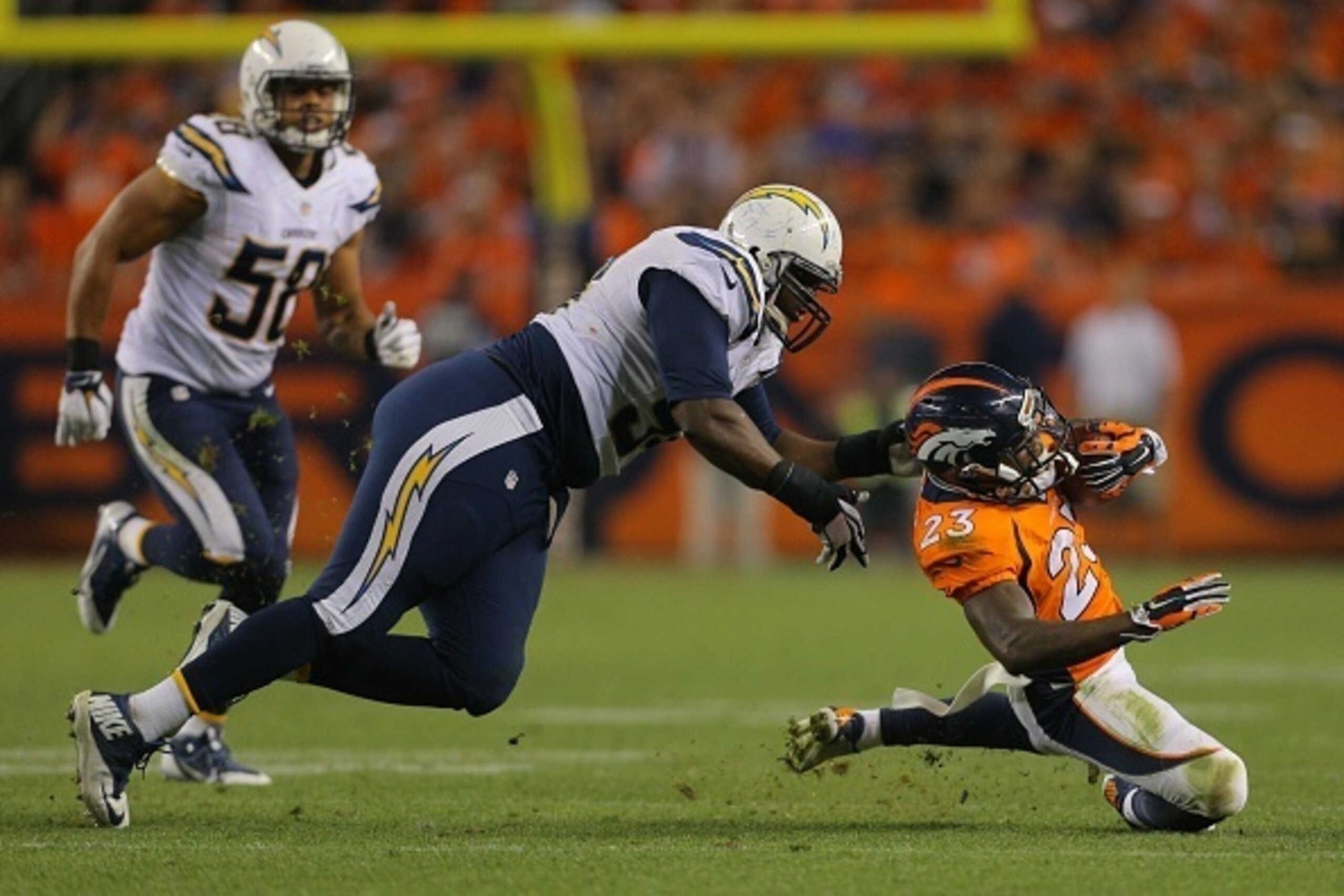 DENVER, CO - OCTOBER 23:  Running back Ronnie Hillman #23 of the Denver Broncos is tackled by defensive end Corey Liuget #94 of the San Diego Chargers during a game at Sports Authority Field at Mile High on October 23, 2014 in Denver, Colorado.  (Photo by
