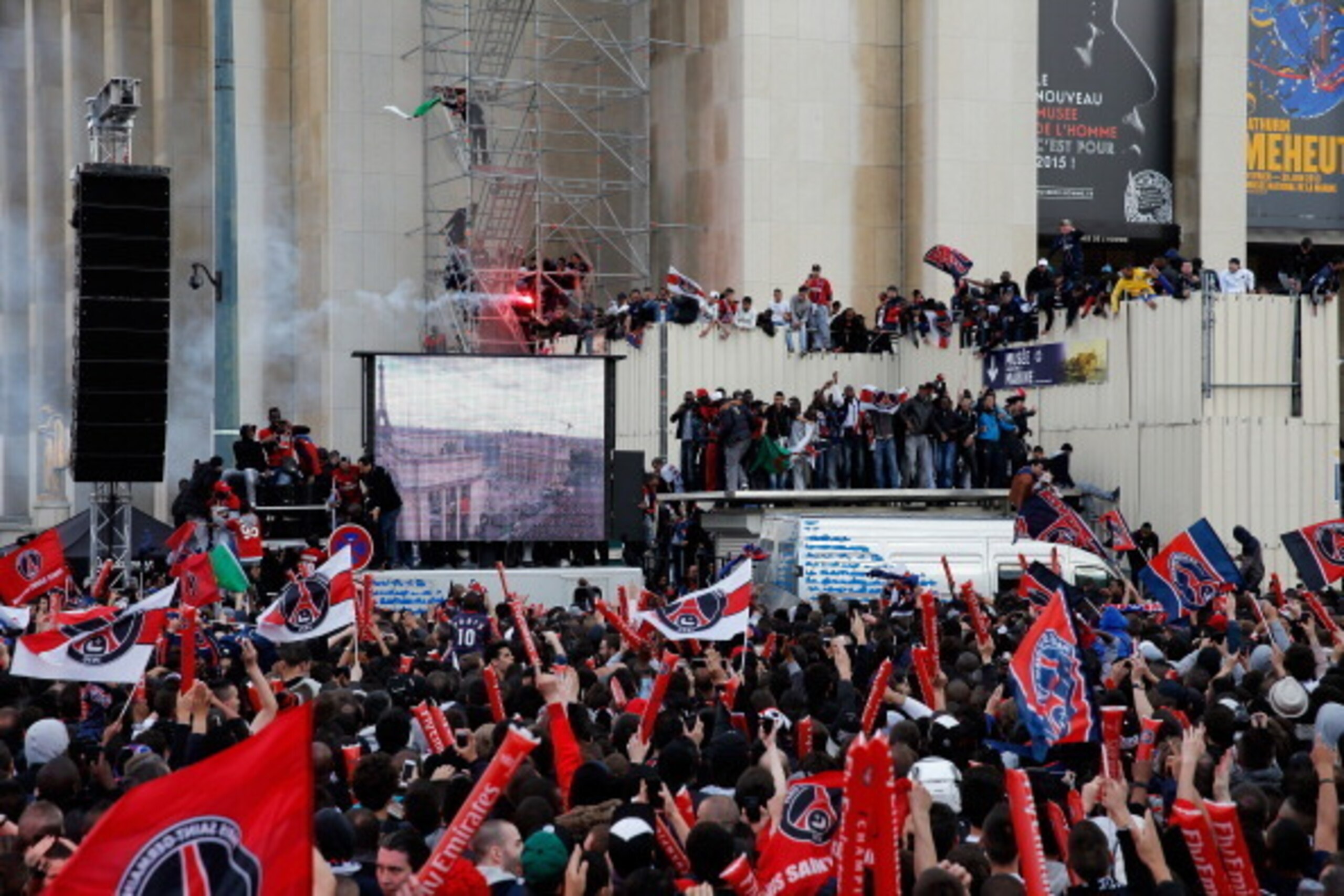 PARIS, FRANCE - MAY 13:  PSG fans celebrate by climbing on cars, buildings and scaffolding in front of Musee d'Ethnographie du Trocadero or Ethnographic Museum of the Trocadero with flares and fireworks after winning Ligue 1 during the Paris Saint-Germain