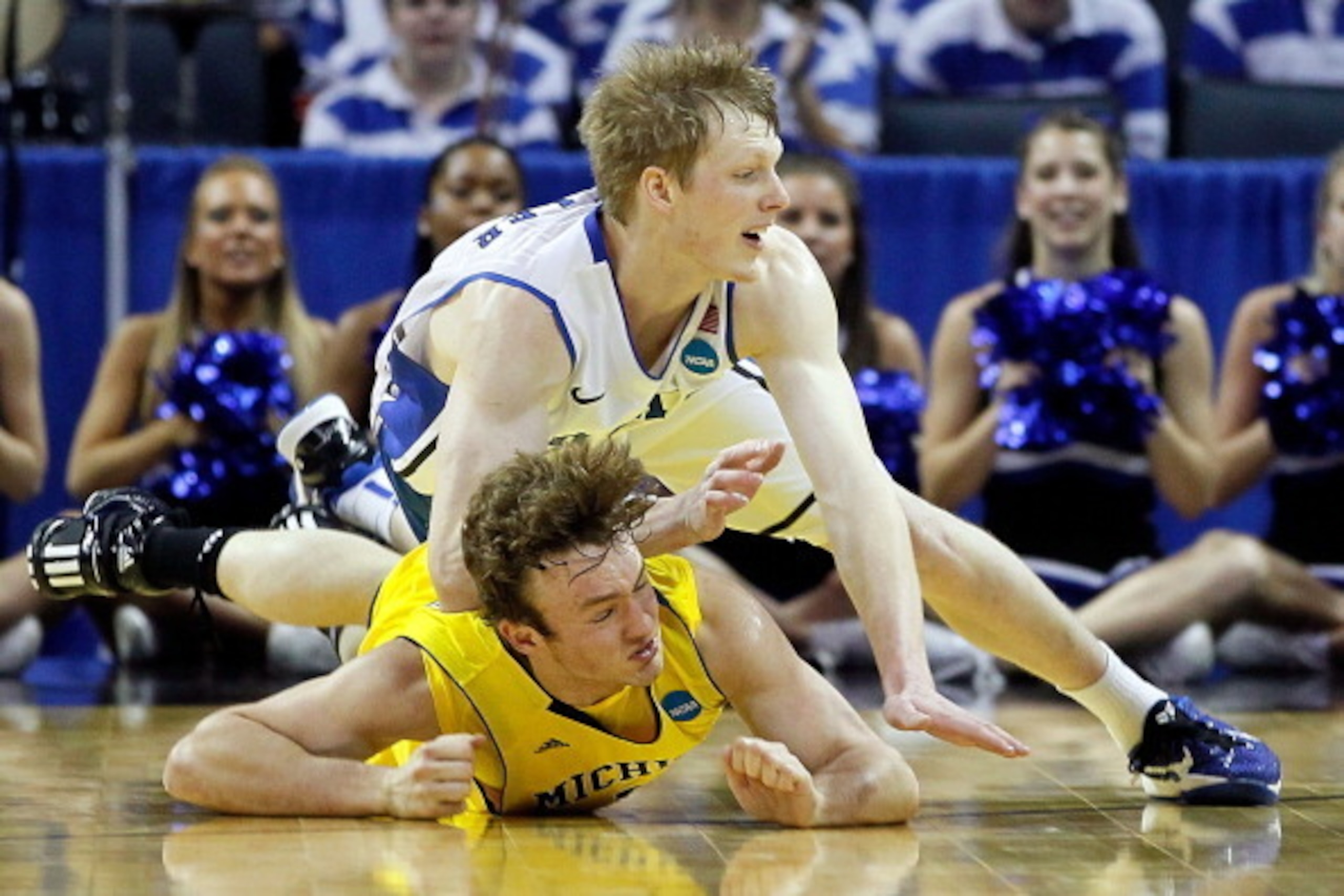 CHARLOTTE, NC - MARCH 20:  Zack Novak #0 of the Michigan Wolverines is landed on after being jumped on by Kyle Singler #12 of the Duke Blue Devils in the first half as they go for a loose ball during the third round of the 2011 NCAA men's basketball tourn