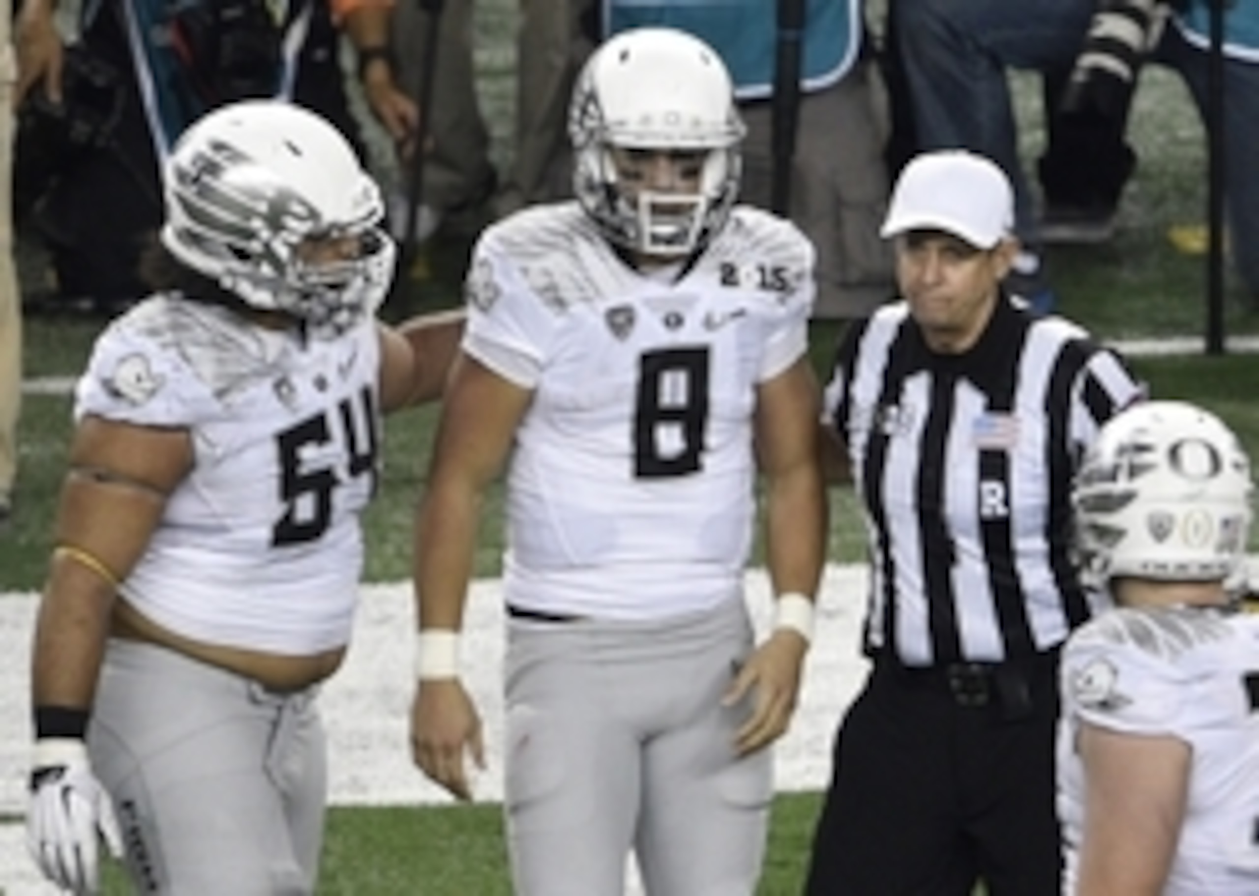 Jan 12, 2015; Arlington, TX, USA; Oregon Ducks quarterback Marcus Mariota (8) walks off the field with offensive lineman Hamani Stevens (54) and game official Greg Burks (right) during the fourth quarter against the Ohio State Buckeyes in the 2015 CFP Nat