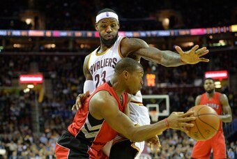 Dec 9, 2014; Cleveland, OH, USA; Toronto Raptors guard Kyle Lowry (7) passes the ball around Cleveland Cavaliers forward LeBron James (23) in the second quarter at Quicken Loans Arena. Mandatory Credit: David Richard-USA TODAY Sports