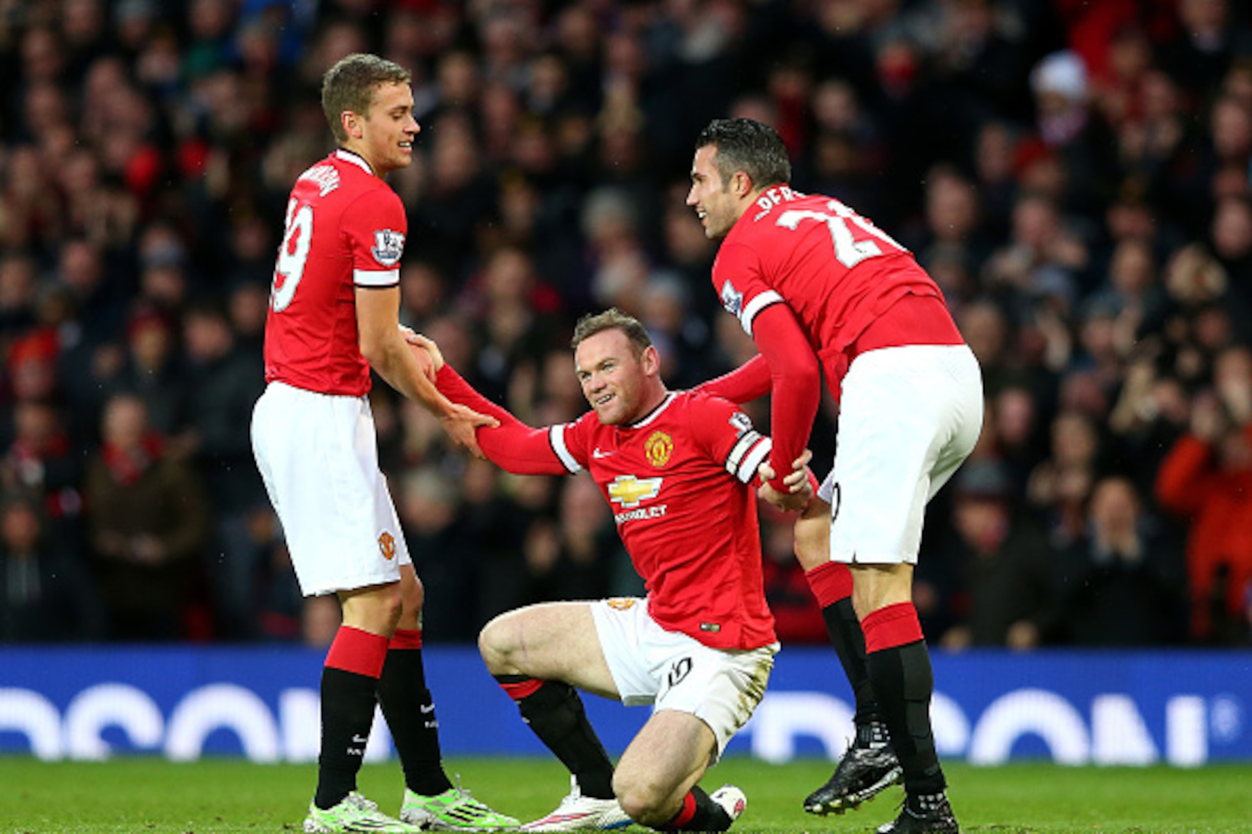 MANCHESTER, ENGLAND - DECEMBER 14:  Wayne Rooney of Manchester United is helped to his feet by James Wilson (L) and Robin van Persie (R) after scoring the first goal during the Barclays Premier League match between Manchester United and Liverpool at Old T
