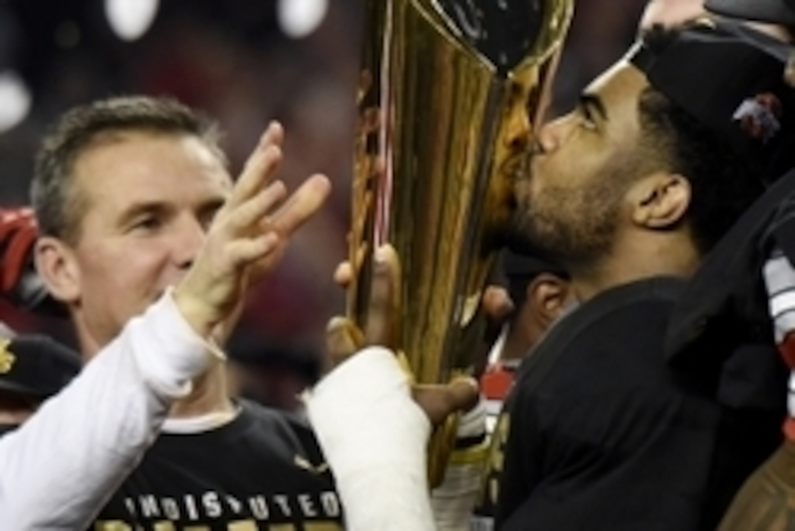 Jan 12, 2015; Arlington, TX, USA; Ohio State Buckeyes running back Ezekiel Elliott (15) kisses the trophy as head coach Urban Meyer hands it to him after their win over the Oregon Ducks in the 2015 CFP National Championship Game at AT&T Stadium. Ohio Stat
