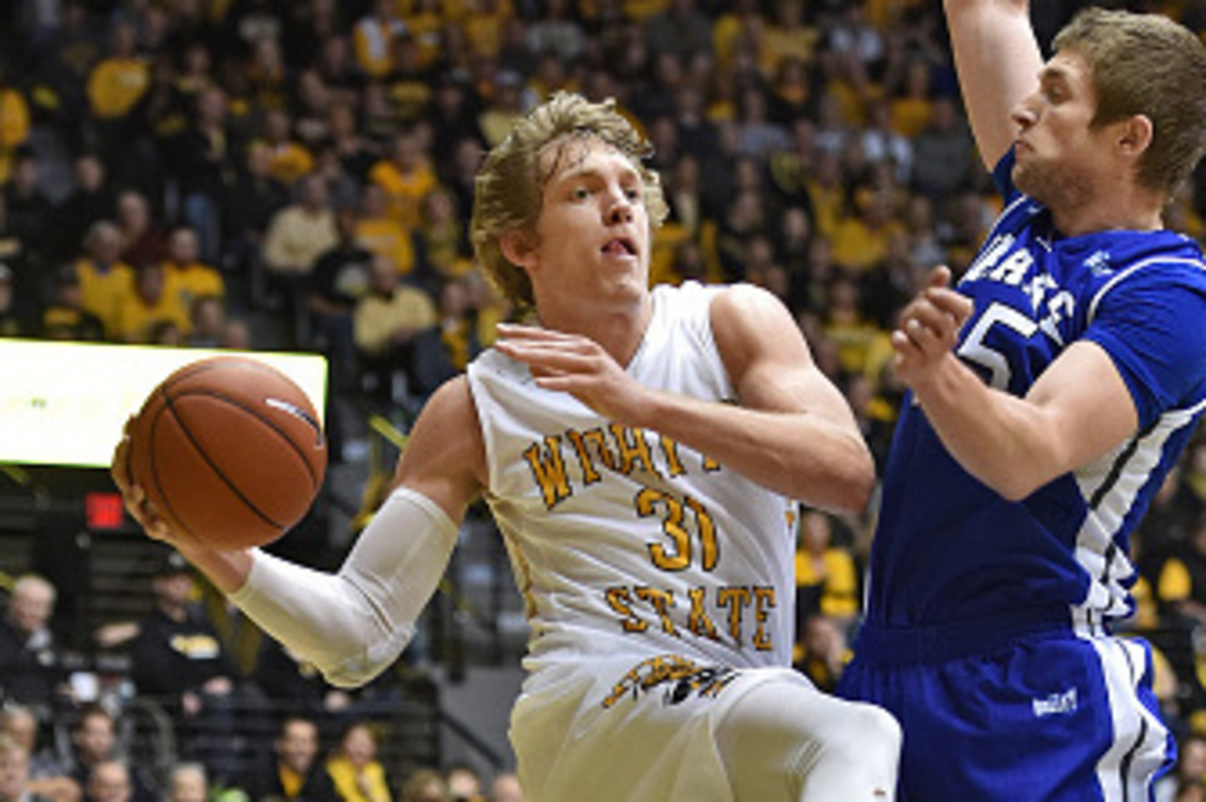 WICHITA, KS - JANUARY 25: Guard Ron Baker #31 of the Wichita State Shockers drives to the basket against guard Chris Caird #25 of the Drake Bulldogs during the first half on January 25, 2015 at Charles Koch Arena in Wichita, Kansas. Wichita State defeated WICHITA, KS - JANUARY 25: Guard Ron Baker #31 of the Wichita State Shockers drives to the basket against guard Chris Caird #25 of the Drake Bulldogs during the first half on January 25, 2015 at Charles Koch Arena in Wichita, Kansas. Wichita State defeated