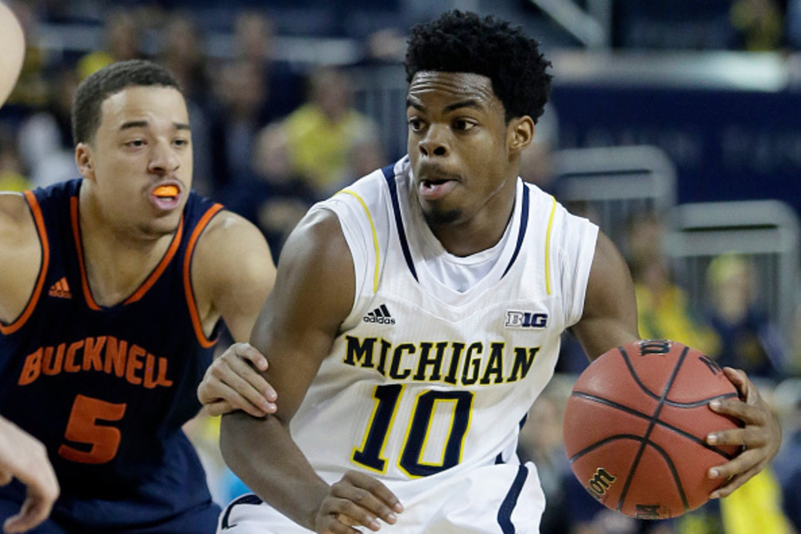 ANN ARBOR, MI - NOVEMBER 17:  Derrick Walton Jr. #10 of the Michigan Wolverines is grabbed by John Azzinaro #5 of the Bucknell Bison while driving to the basket during the first half at Crisler Arena on November 17, 2014 in Ann Arbor, Michigan. (Photo by 