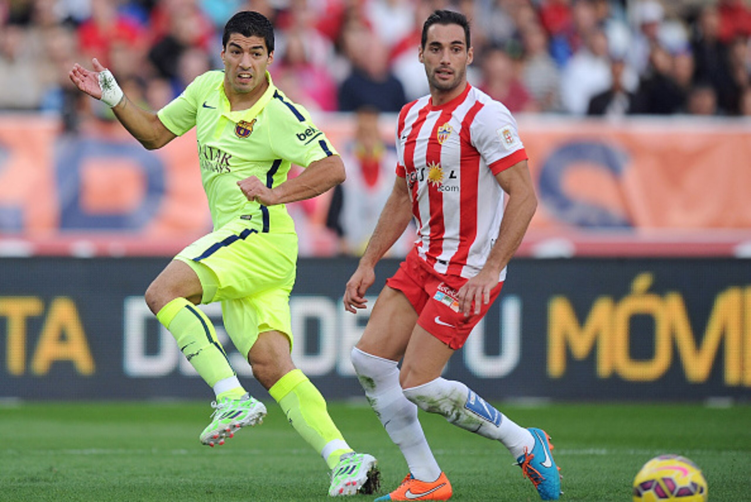 ALMERIA, SPAIN - NOVEMBER 08:  Luis Suarez of FC Barcelona passes the ball past Angel Trujillo of UD Almeria during the La Liga match between UD Almeria and FC Barcelona at estadio de los Juegos Mediterraneos on November 8, 2014 in Almeria, Spain.  (Photo