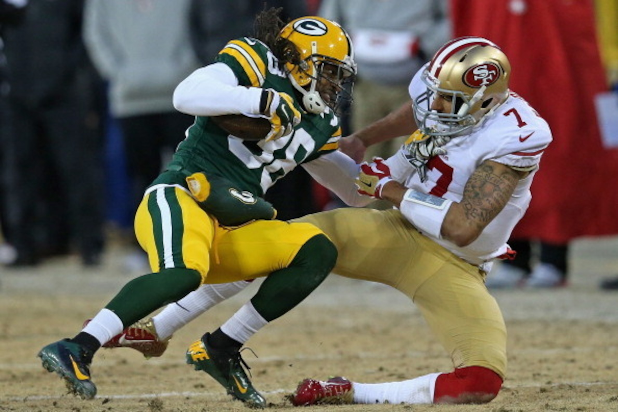 GREEN BAY, WI - JANUARY 05:  Colin Kaepernick #7 of the San Fransico 49ers tackles Tramon Williams #38 of the Green Bay Packers after Williams intercepted a pass during an NFC Wild Card Playoff game at Lambeau Field on January 5, 2014 in Green Bay, Wiscon
