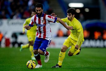 MADRID, SPAIN - DECEMBER 14: Arda Turan (L) competes for the ball with Manuel Trigueros (R) of Villarreal CF during the La Liga match between Club Atletico de Madrid and Villarreal CF at Vicente Calderon Stadium on December 14, 2014 in Madrid, Spain.  (Ph