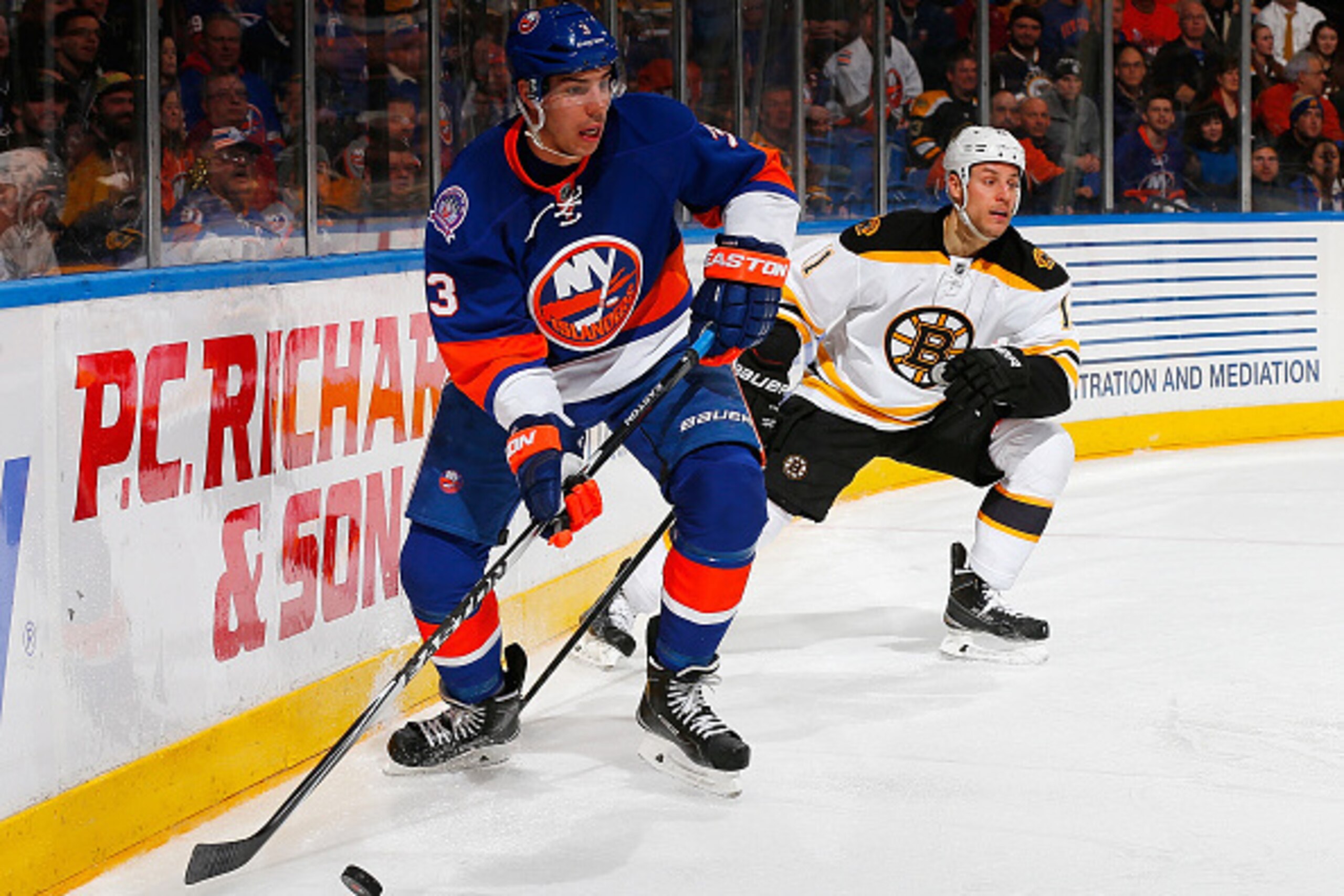 UNIONDALE, NY - JANUARY 29: Travis Hamonic #3 of the New York Islanders is pursued by Gregory Campbell #11 of the Boston Bruins at Nassau Veterans Memorial Coliseum on January 29, 2015 in Uniondale, New York.  (Photo by Mike Stobe/NHLI via Getty Images)