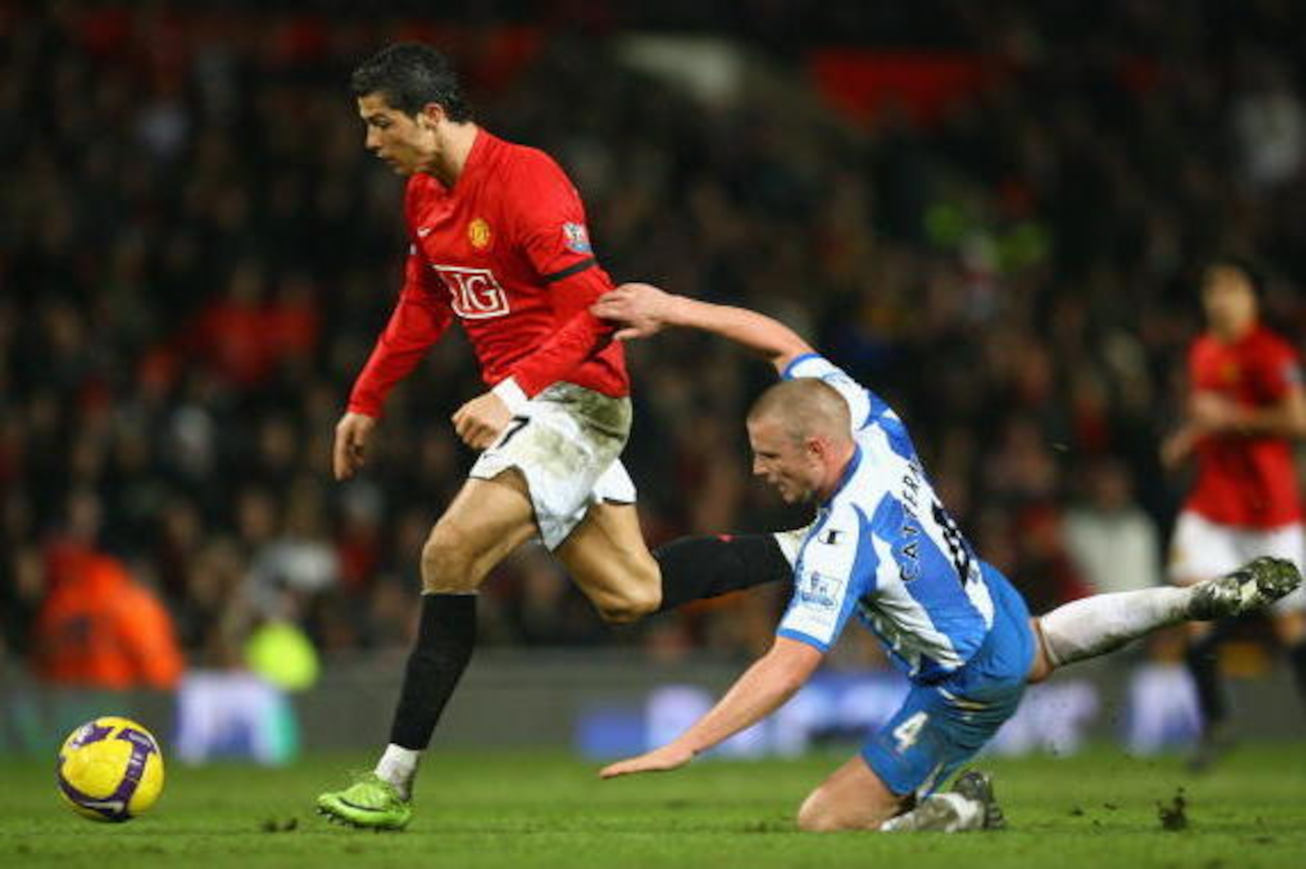 MANCHESTER, UNITED KINGDOM - JANUARY 14:  Cristiano Ronaldo of Manchester United evades the challenge of Lee Cattermole of Wigan Athletic during the Barclays Premier League match between Manchester United and Wigan Athletic at Old Trafford on January 14, 