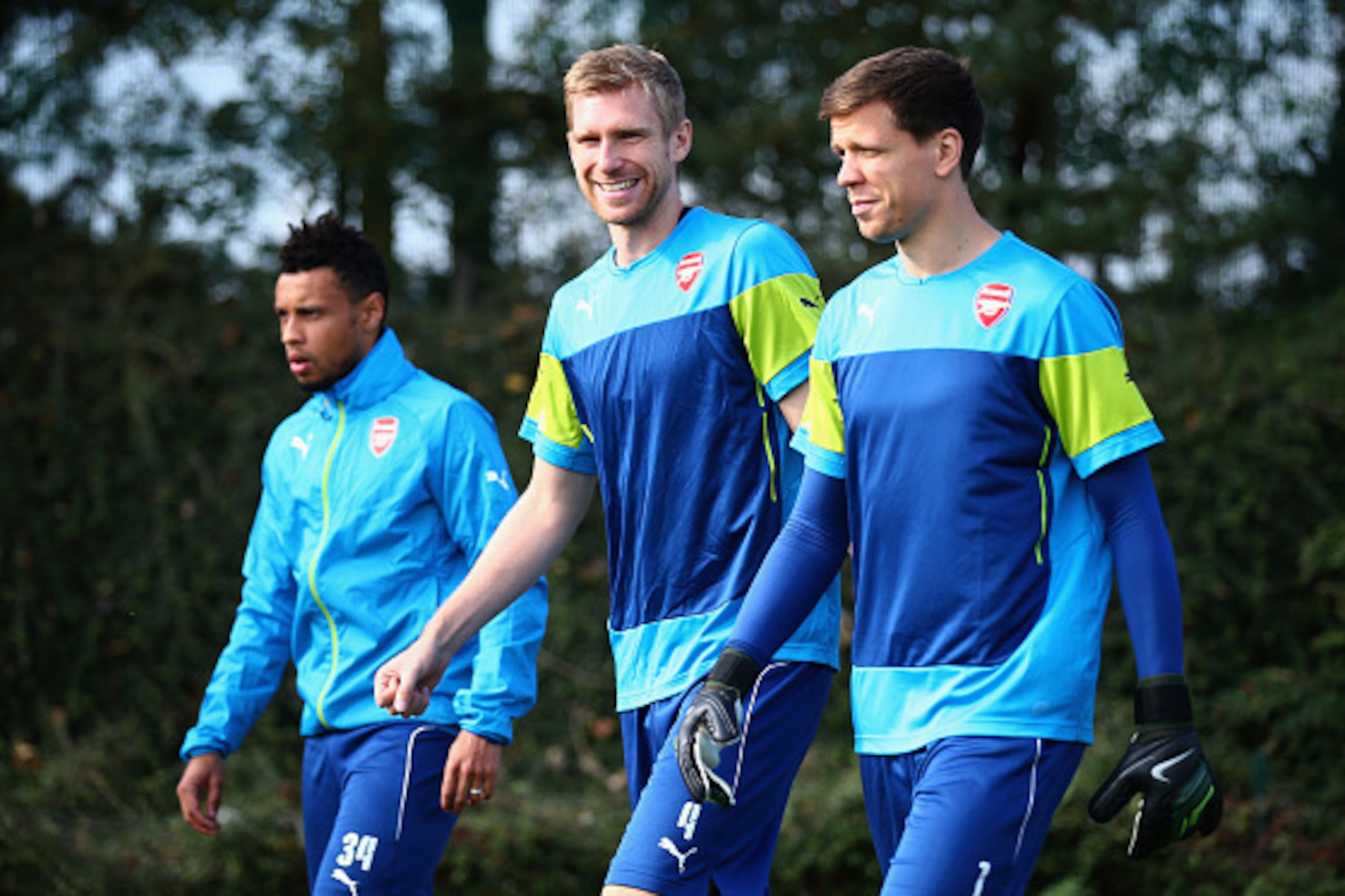 ST ALBANS, ENGLAND - SEPTEMBER 30:  Per Mertesacker of Arsenal (C) smiles with Wojciech Szczesny (R) and Francis Coquelin (L) during an Arsenal training session ahead of their UEFA Champions League Group D match against Galatasaray at London Colney on Sep