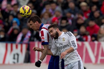 MADRID, SPAIN - FEBRUARY 07: Mario Mandzukic of Atletico de Madrid wins the header before Daniel Carvajal of Real Madrid CF during the La Liga match between Club Atletico de Madrid and Real Madrid CF at Vicente Calderon Stadium on February 7, 2015 in Madr