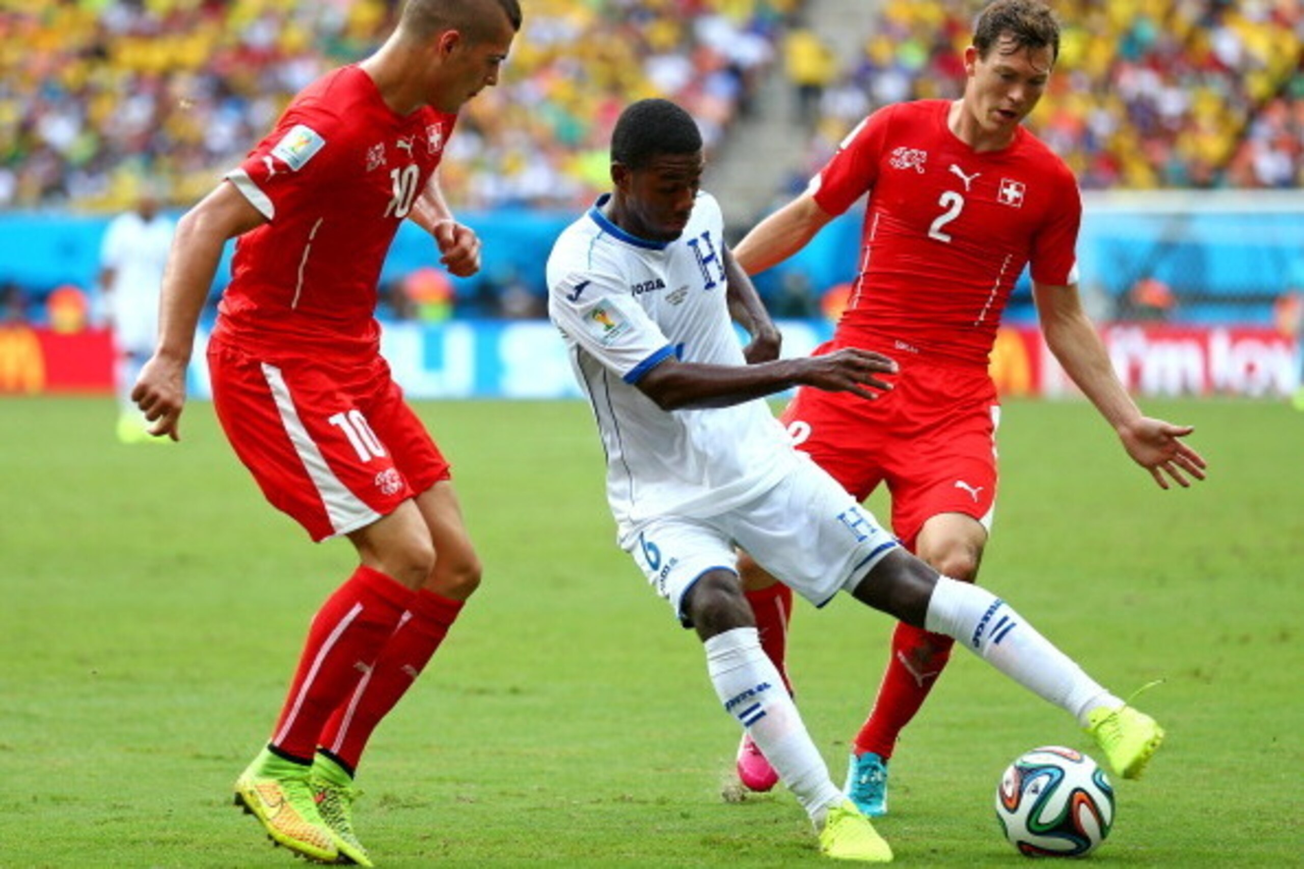 MANAUS, BRAZIL - JUNE 25: Juan Carlos Garcia of Honduras controls the ball as Granit Xhaka and Stephan Lichtsteiner of Switzerland give chase during the 2014 FIFA World Cup Brazil Group E match between Honduras and Switzerland at Arena Amazonia on June 25