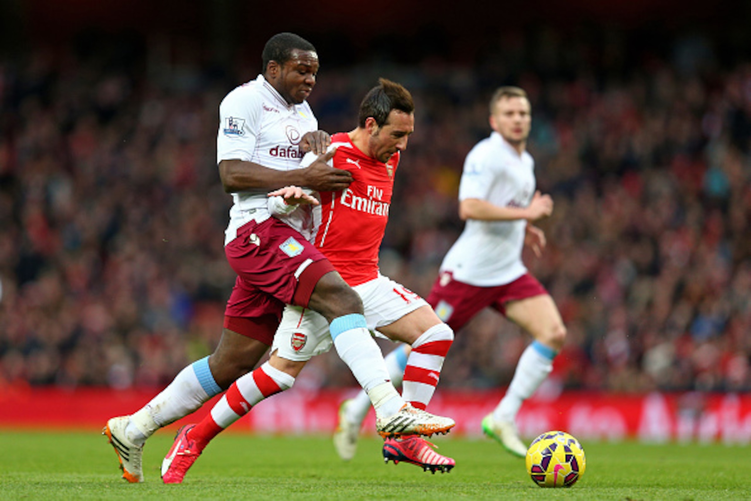 LONDON, ENGLAND - FEBRUARY 01:  Santi Cazorla of Arsenal holds off the challenge from Jores Okore of Aston Villa during the Barclays Premier League match between Arsenal and Aston Villa at the Emirates Stadium on February 1, 2015 in London, England.  (Pho