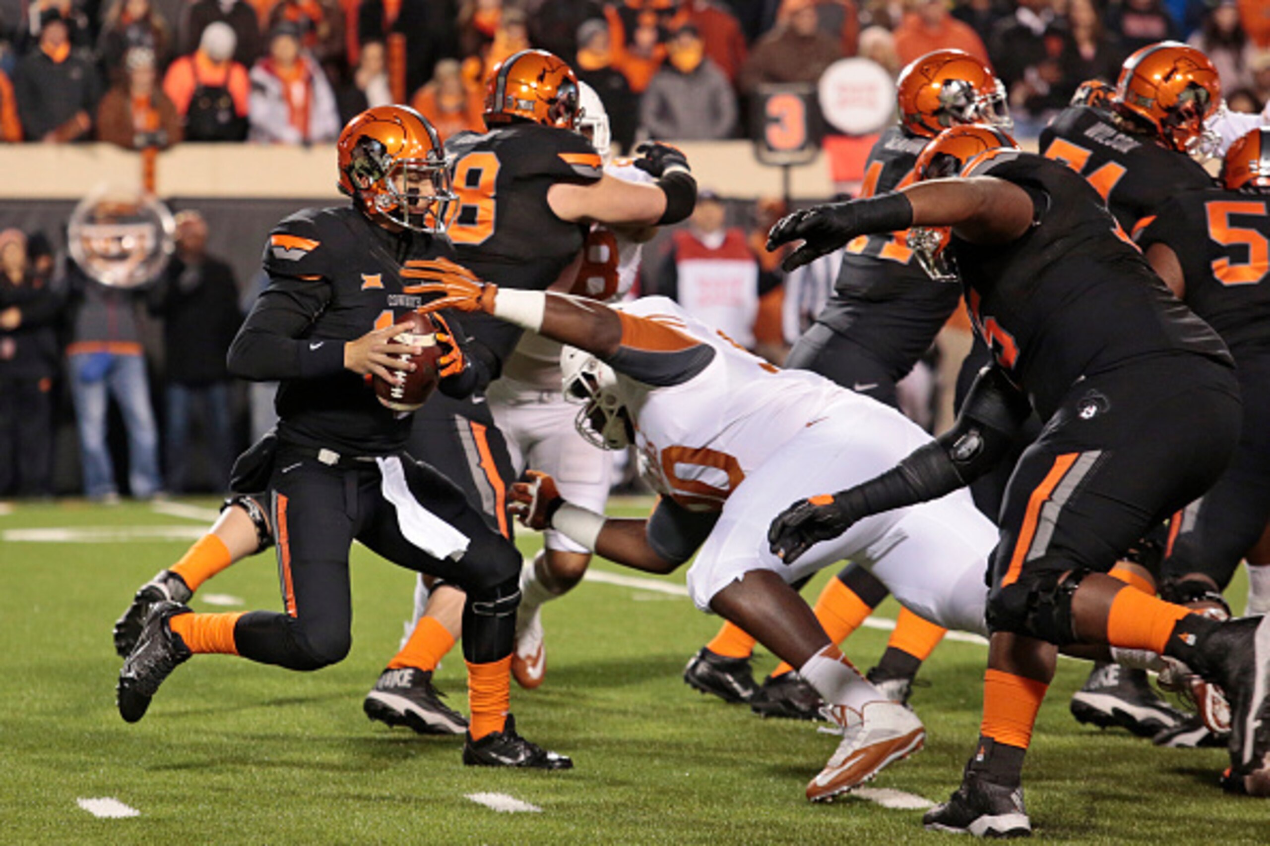 STILLWATER, OK - NOVEMBER 15:   Quarterback Daxx Garman #12 of the Oklahoma State Cowboys tries to avoid defensive tackle Malcom Brown #90 of the Texas Longhorns November 15, 2014 at Boone Pickens Stadium in Stillwater, Oklahoma. The Longhorns defeated th