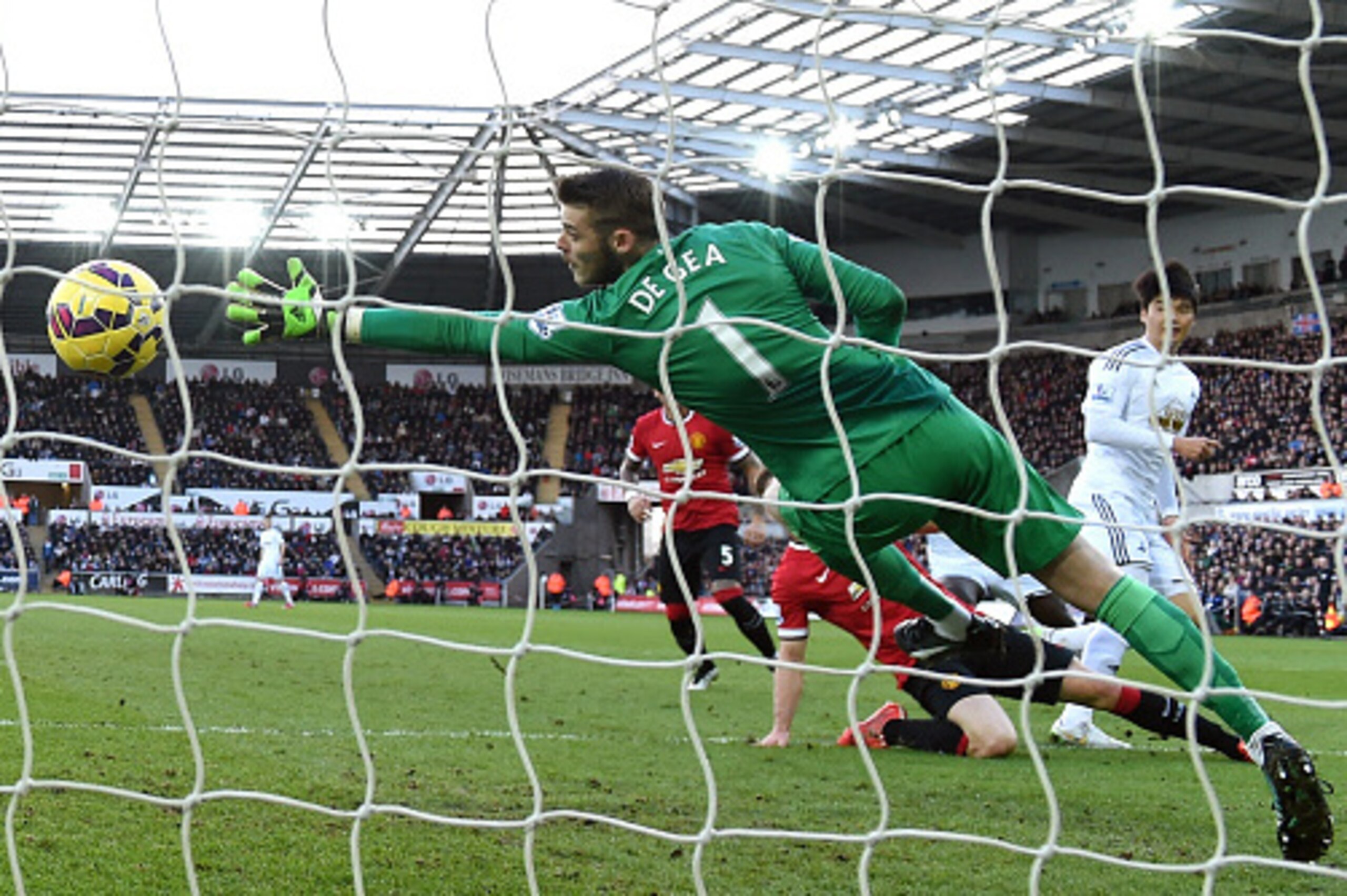 SWANSEA, WALES - FEBRUARY 21:  Swansea player Ki Sung - Yueng (r) scores the first Swansea goal past a diving David de Gea of Manchester United during the Barclays Premier League match between Swansea City and Manchester United at Liberty Stadium on Febru