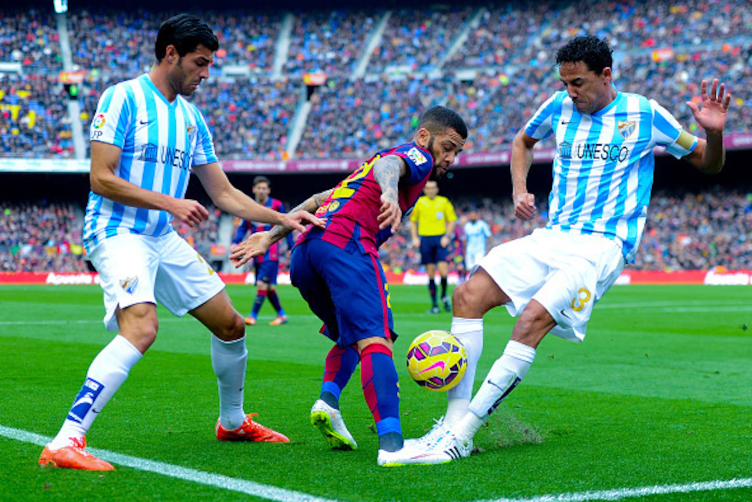 BARCELONA, SPAIN - FEBRUARY 21:  Dani Alves of FC Barcelona competes for the ball with Welligton Robson (R) and Miguel Torres of Malaga CF during the La Liga match between FC Barcelona and Malaga CF at Camp Nou on February 21, 2015 in Barcelona, Spain.  (