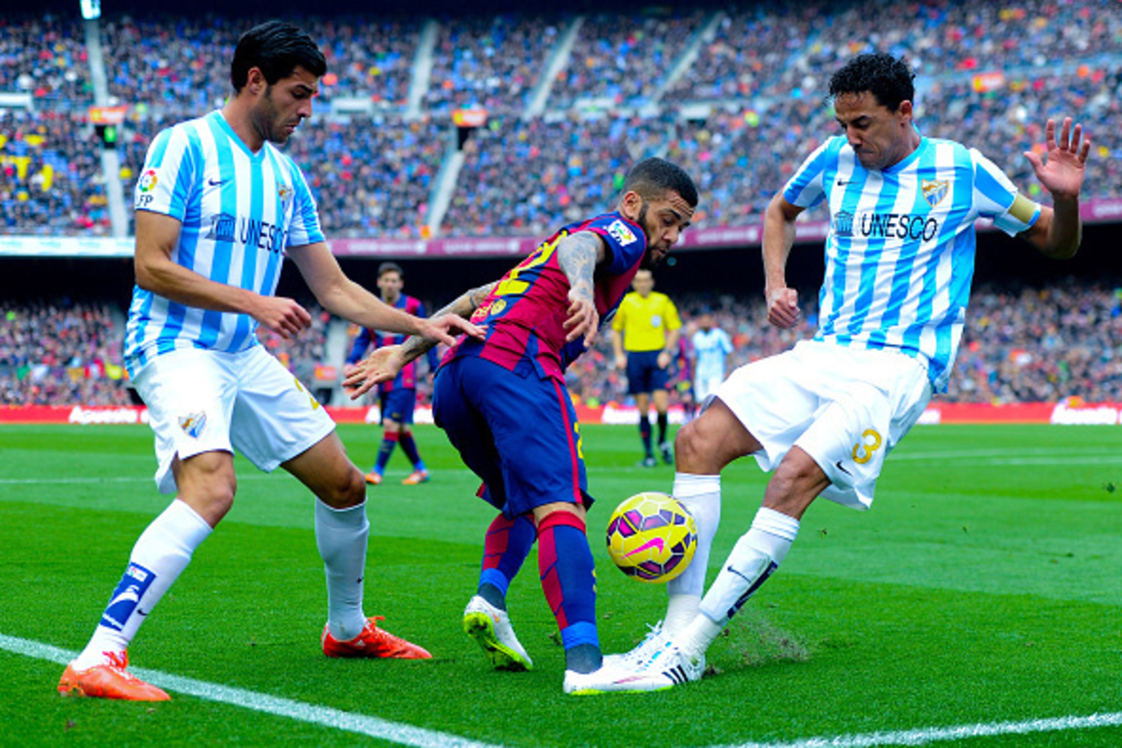 BARCELONA, SPAIN - FEBRUARY 21:  Dani Alves of FC Barcelona competes for the ball with Welligton Robson (R) and Miguel Torres of Malaga CF during the La Liga match between FC Barcelona and Malaga CF at Camp Nou on February 21, 2015 in Barcelona, Spain.  (