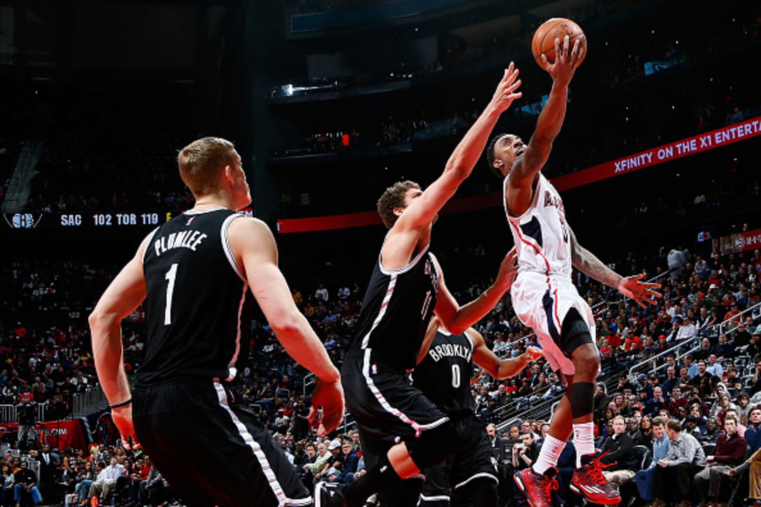 ATLANTA, GA - JANUARY 28:  Jeff Teague #0 of the Atlanta Hawks lays in a basket against Brook Lopez #11 and Mason Plumlee #1 of the Brooklyn Nets at Philips Arena on January 28, 2015 in Atlanta, Georgia.  NOTE TO USER: User expressly acknowledges and agre