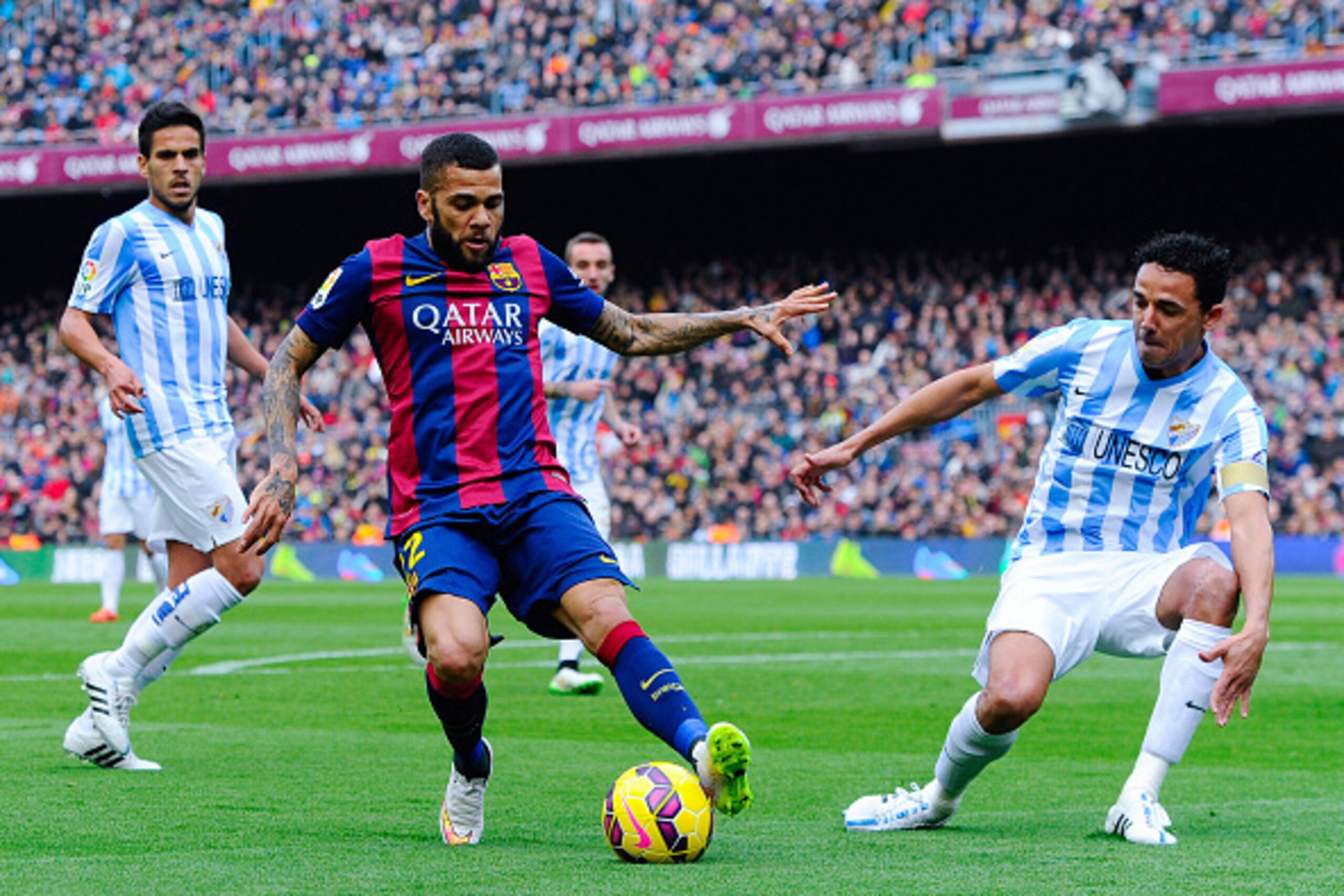 BARCELONA, SPAIN - FEBRUARY 21:  Dani Alves of FC Barcelona competes for the ball with Welligton Robson (R) and Miguel Torres of Malaga CF during the La Liga match between FC Barcelona and Malaga CF at Camp Nou on February 21, 2015 in Barcelona, Spain.  (