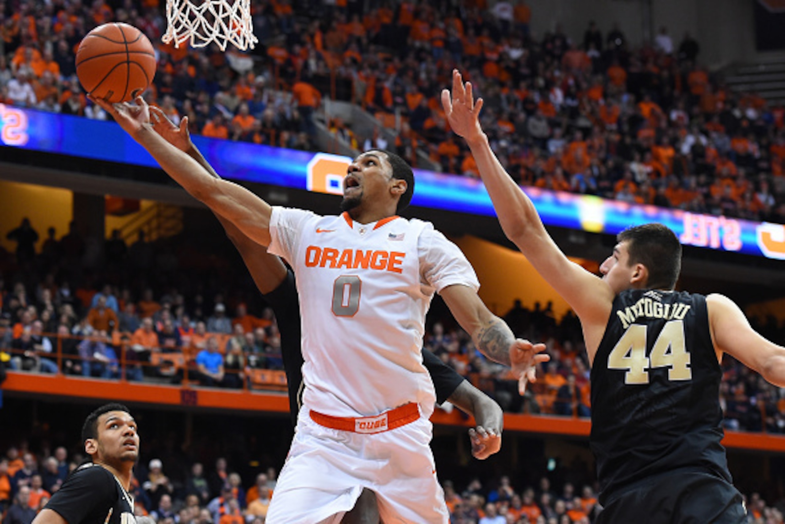 SYRACUSE, NY - JANUARY 13:  Michael Gbinije #0 of the Syracuse Orange shoots the ball around the defense of Konstantinos Mitoglou #44 of the Wake Forest Demon Deacons during the second half at the Carrier Dome on January 13, 2015 in Syracuse, New York.  S