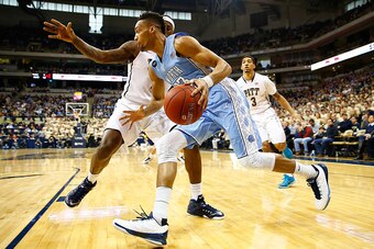 PITTSBURGH, PA - FEBRUARY 14: J.P. Tokoto #13 of the North Carolina Tarheels drives the baseline past Jamel Artis #1 of the Pittsburgh Panthers in the first half during the game at Petersen Events Center on February 14, 2015 in Pittsburgh, Pennsylvania.  