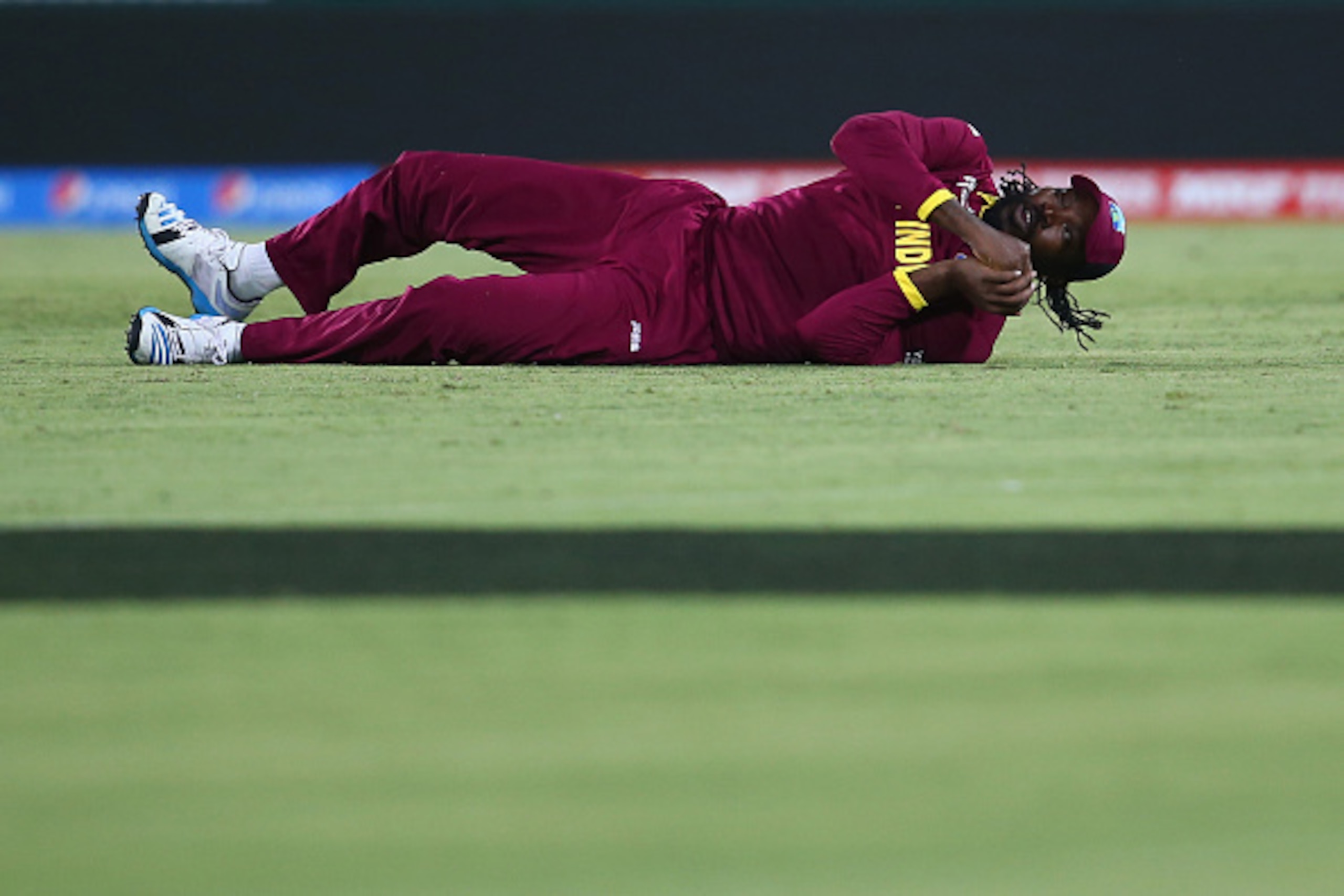 CANBERRA, AUSTRALIA - FEBRUARY 24:  Chris Gayle of West Indies rolls on the ground as he celebrates taking the catch to remove Elton Chigumbura of Zimbabwe during the 2015 ICC Cricket World Cup match between the West Indies and Zimbabwe at Manuka Oval on 