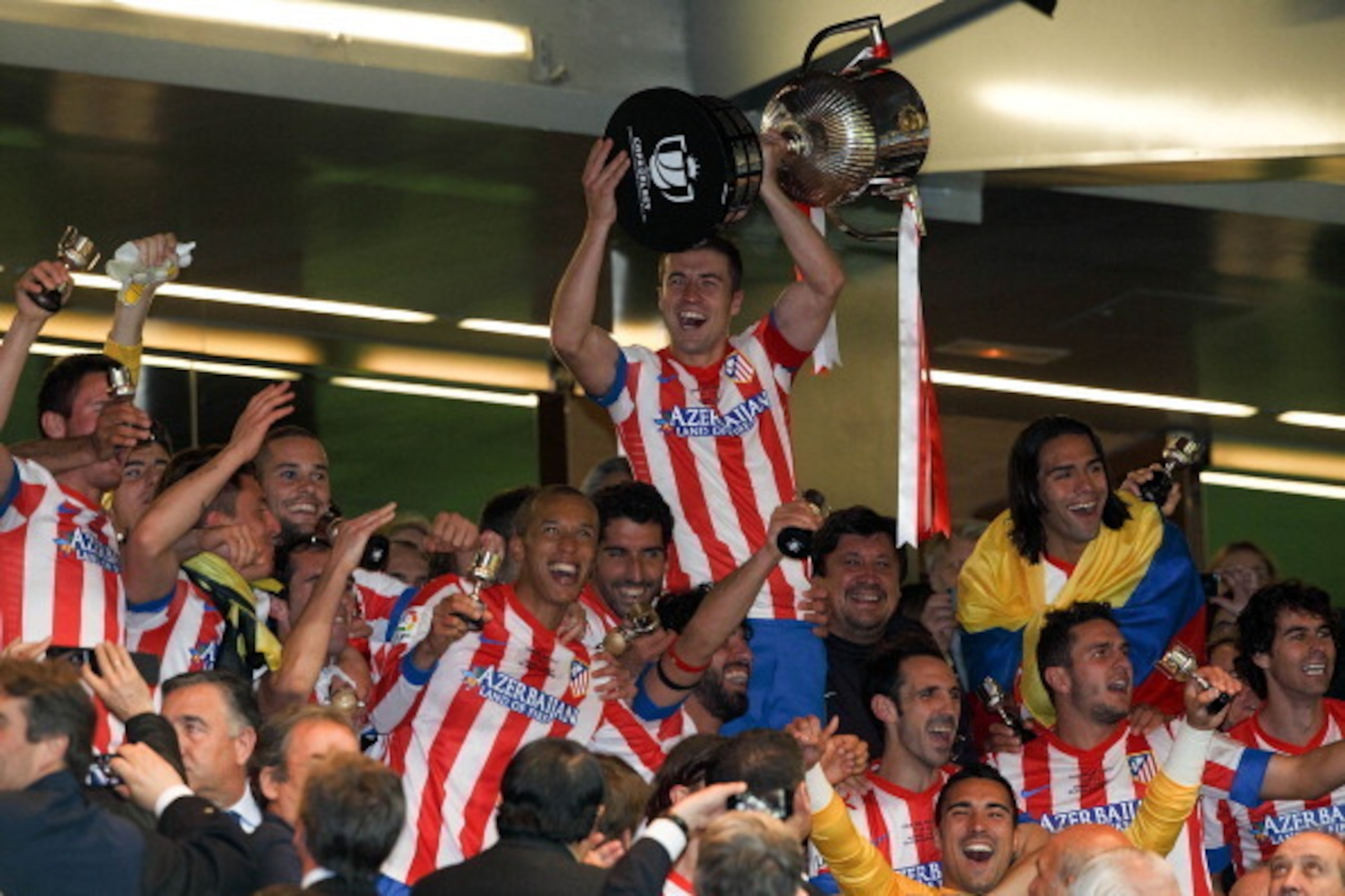 MADRID, SPAIN - MAY 17: Gabriel Gabi fernandez of Atletico de Madrid holds the trophy in celebration surrounded by teammates as Radamel Falcao (R) after the Copa del Rey Final match between Real Madrid CF and Club Atletico de Madrid at Estadio Santiago Be