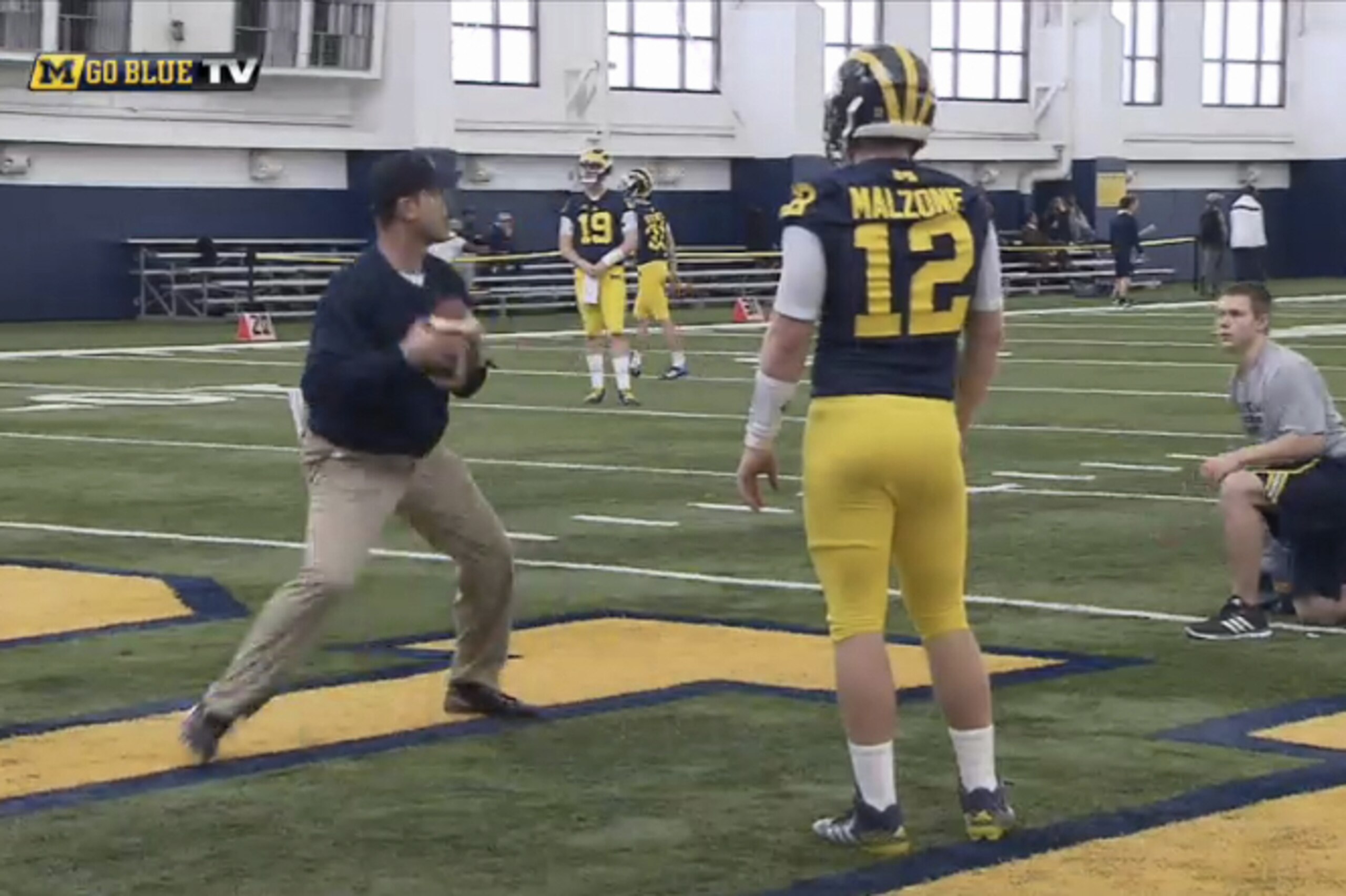 Jim Harbaugh works with quarterback Alex Malzone during spring practice.