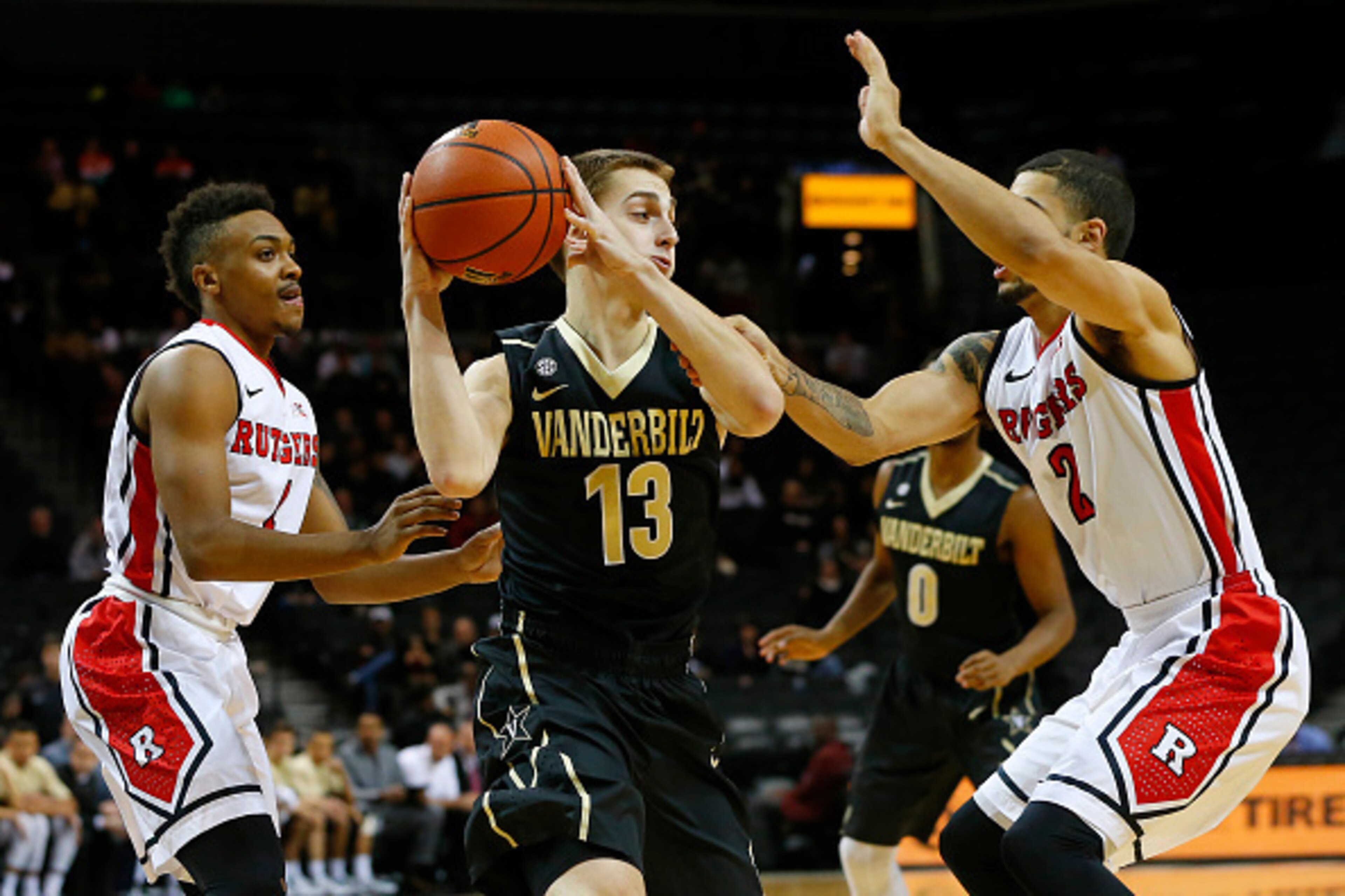 NEW YORK, NY - NOVEMBER 28: Riley LaChance #13 of the Vanderbilt Commodores is defended by Myles Mack #4 and Bishop Daniels #2 of the Rutgers Scarlet Knights during the first half of a game in the Barclays Center Classic men's basketball tournament at Bar