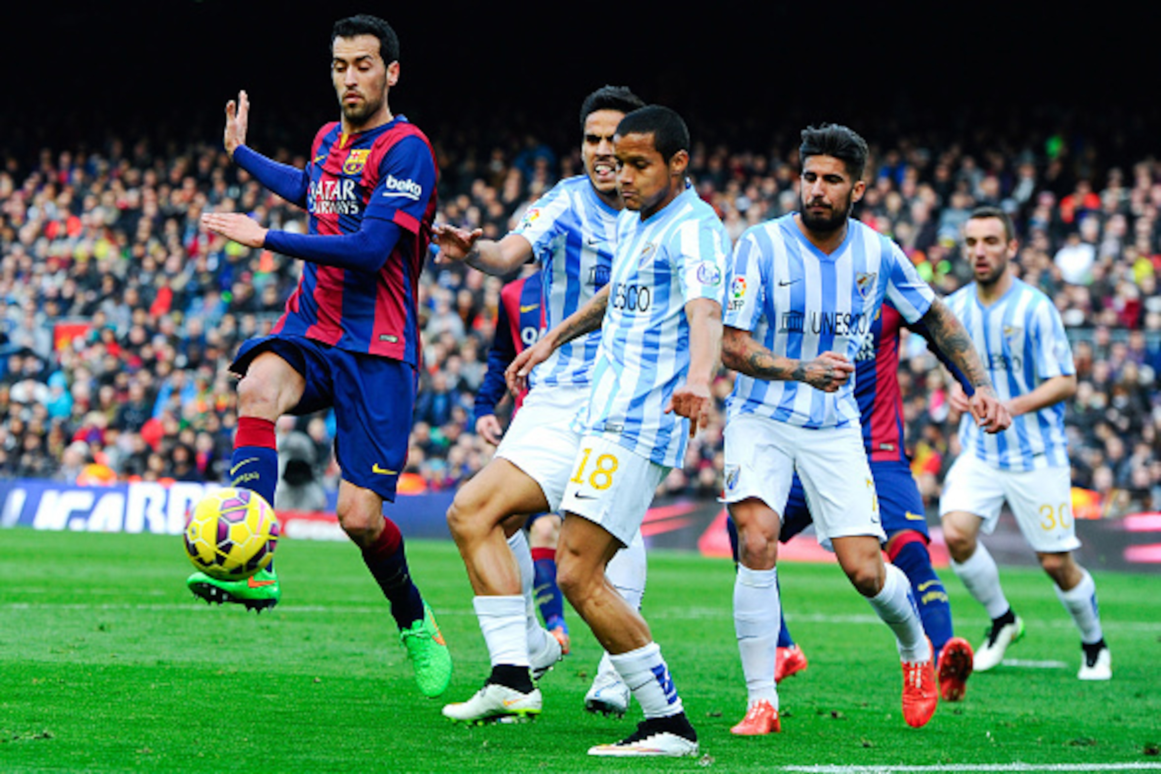 BARCELONA, SPAIN - FEBRUARY 21: Welligton Robson of Malaga CF clears the ball under pressure from Sergio Busquets of FC Barcelona during the La Liga match between FC Barcelona and Malaga CF at Camp Nou on February 21, 2015 in Barcelona, Spain. (Photo by BARCELONA, SPAIN - FEBRUARY 21: Welligton Robson of Malaga CF clears the ball under pressure from Sergio Busquets of FC Barcelona during the La Liga match between FC Barcelona and Malaga CF at Camp Nou on February 21, 2015 in Barcelona, Spain. (Photo by