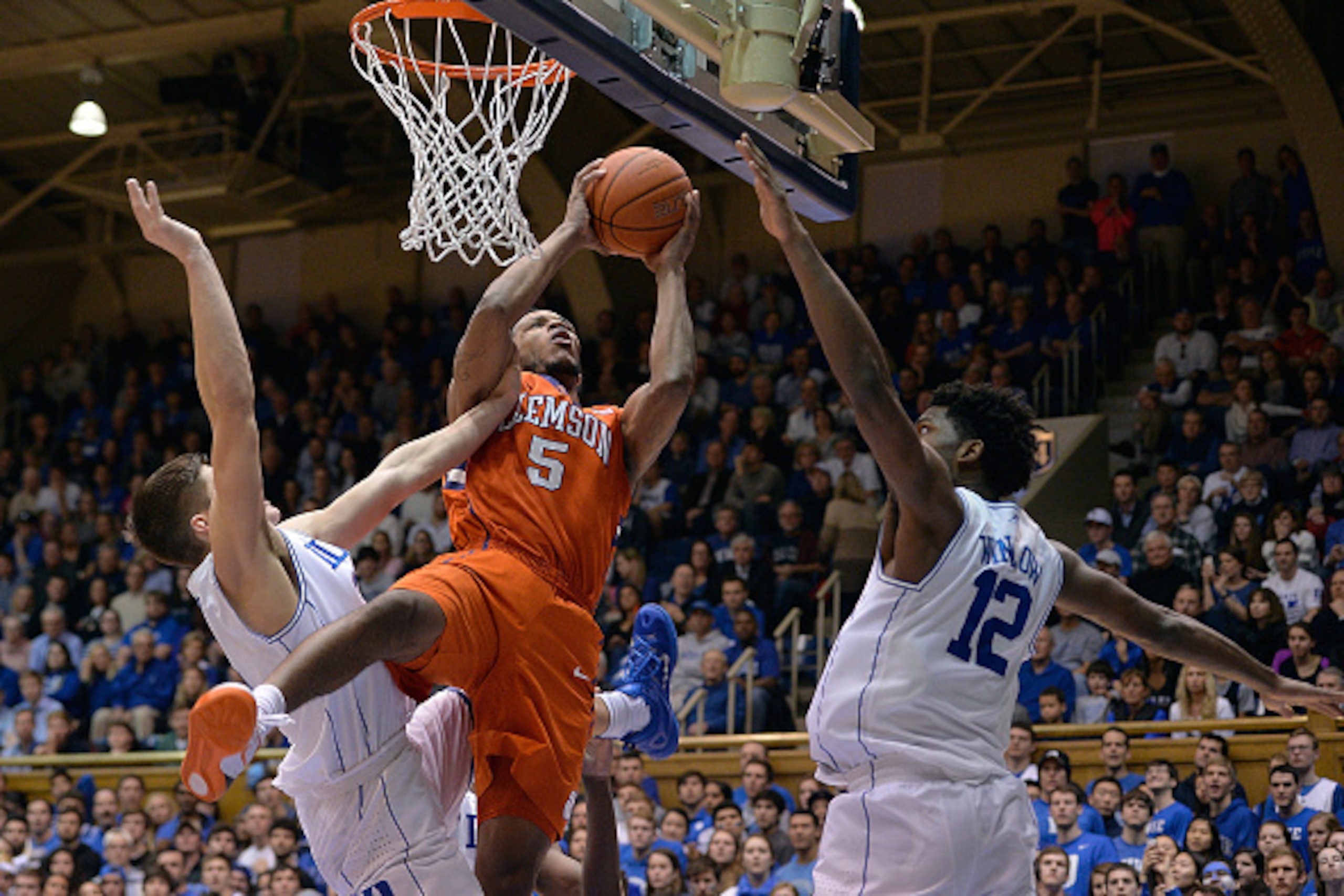DURHAM, NC - FEBRUARY 21:  Jaron Blossomgame #5 of the Clemson Tigers is fouled as he drives between Grayson Allen #3 and Justise Winslow #12 of the Duke Blue Devils during their game at Cameron Indoor Stadium on February 21, 2015 in Durham, North Carolin