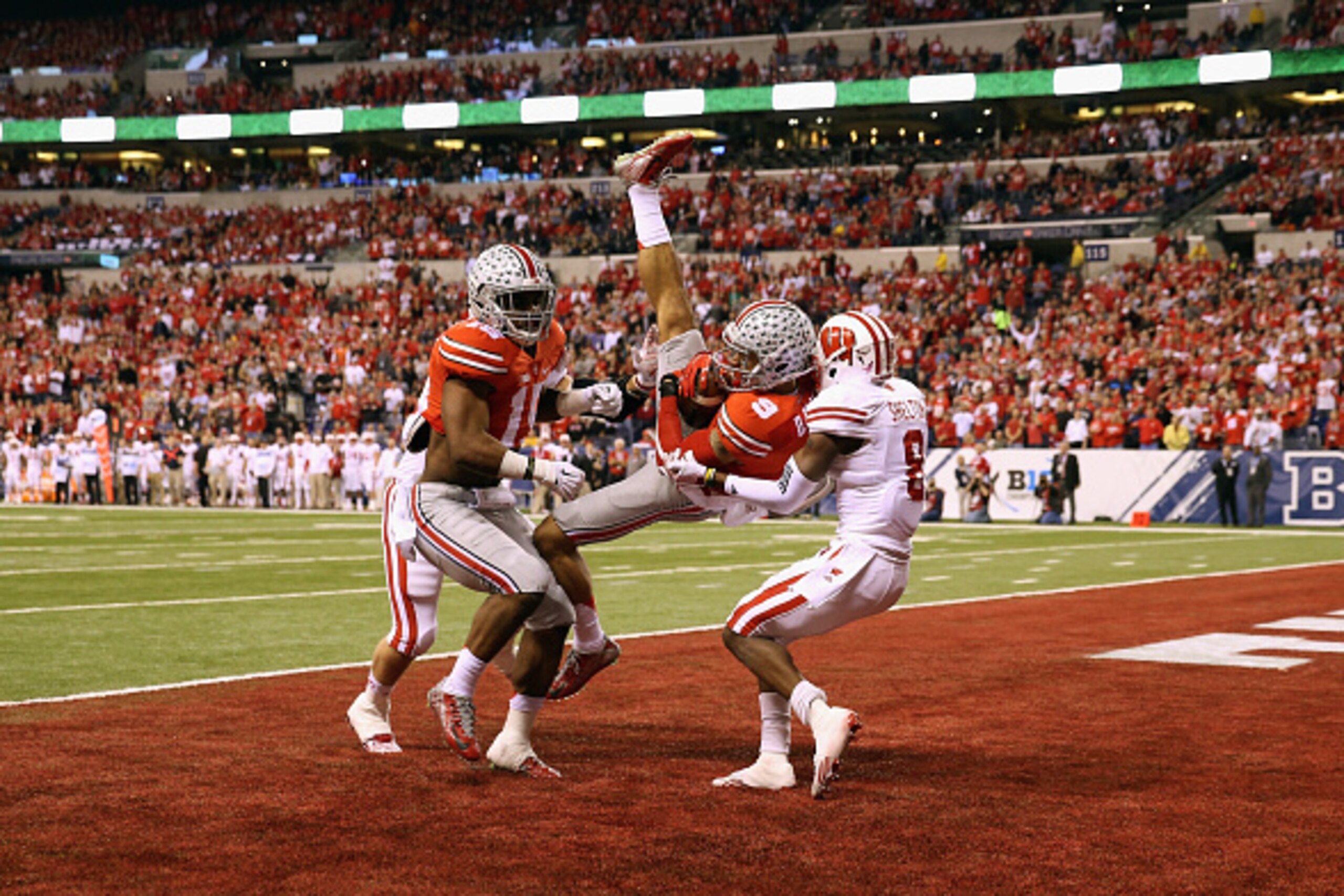 INDIANAPOLIS, IN - DECEMBER 06:  Devin Smith #9 of the Ohio State Buckeyes catches the ball over Sojourn Shelton #8 of the Wisconsin Badgers to score a touchdown in the first quarter of the Big Ten Championship game at Lucas Oil Stadium on December 6, 201
