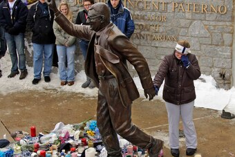 A woman pays her respects at the statue of Joe Paterno after his death on Jan. 22, 2012.