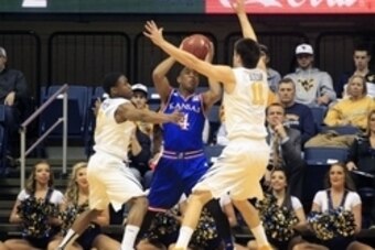 Feb 16, 2015; Morgantown, WV, USA; Kansas Jayhawks guard Devonte Graham (4) is trapped with the ball by West Virginia Mountaineers guard Juwan Staten (3) and forward Nathan Adrian (11) during the first half at the WVU Coliseum. Mandatory Credit: Charles L