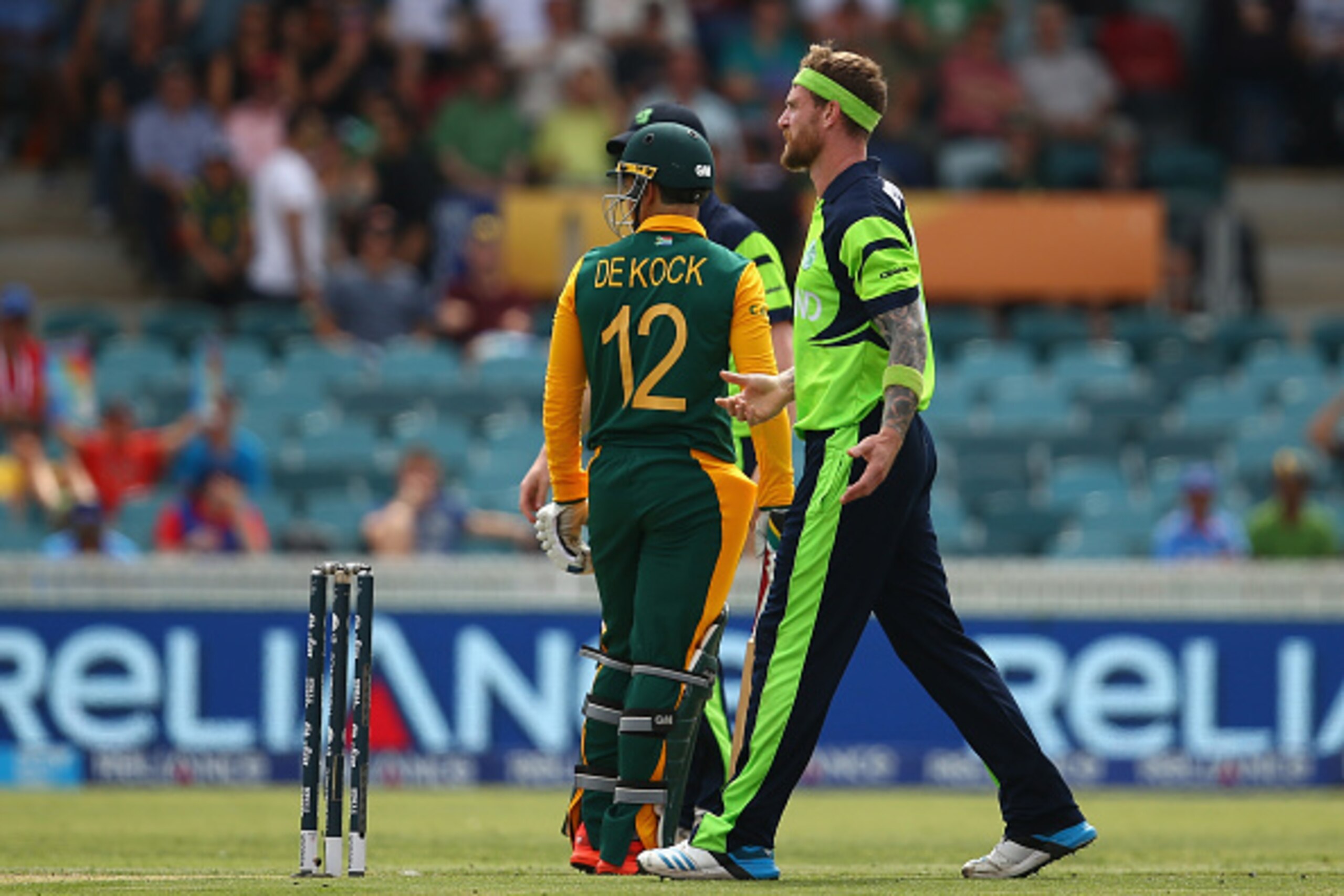CANBERRA, AUSTRALIA - MARCH 03: Quinton de Kock of South Africa looks back as John Mooney of Ireland discusses referring a not out decision with his captain during the 2015 ICC Cricket World Cup match between South Africa and Ireland at Manuka Oval on Mar