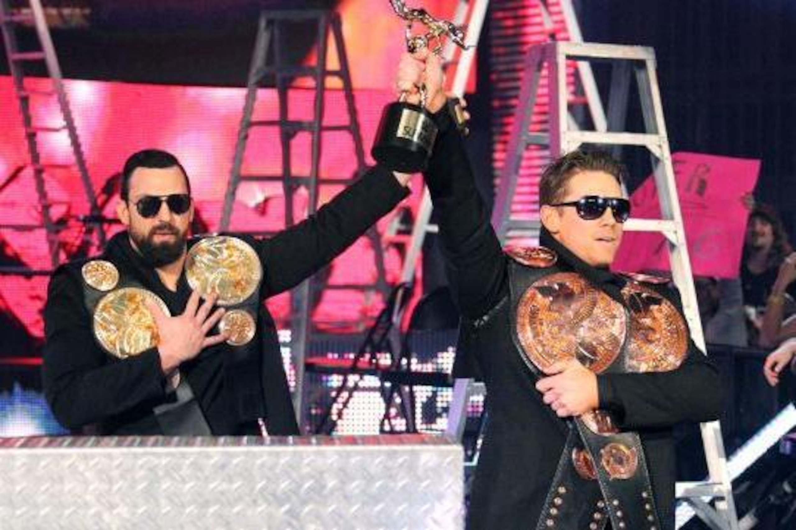 Damien MIzdow holds replica tag titles while The Miz carries around the real ones. Damien MIzdow holds replica tag titles while The Miz carries around the real ones.
