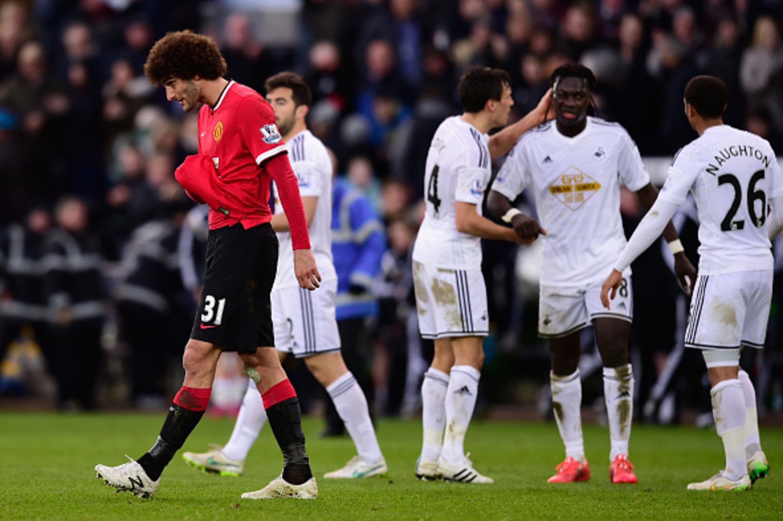 SWANSEA, WALES - FEBRUARY 21: Marouane Fellani (l) of Manchester United reacts as Bafetimbi Gomis of Swansea (2nd r) and team mates celebrate after the Barclays Premier League match between Swansea City and Manchester United at Liberty Stadium on February