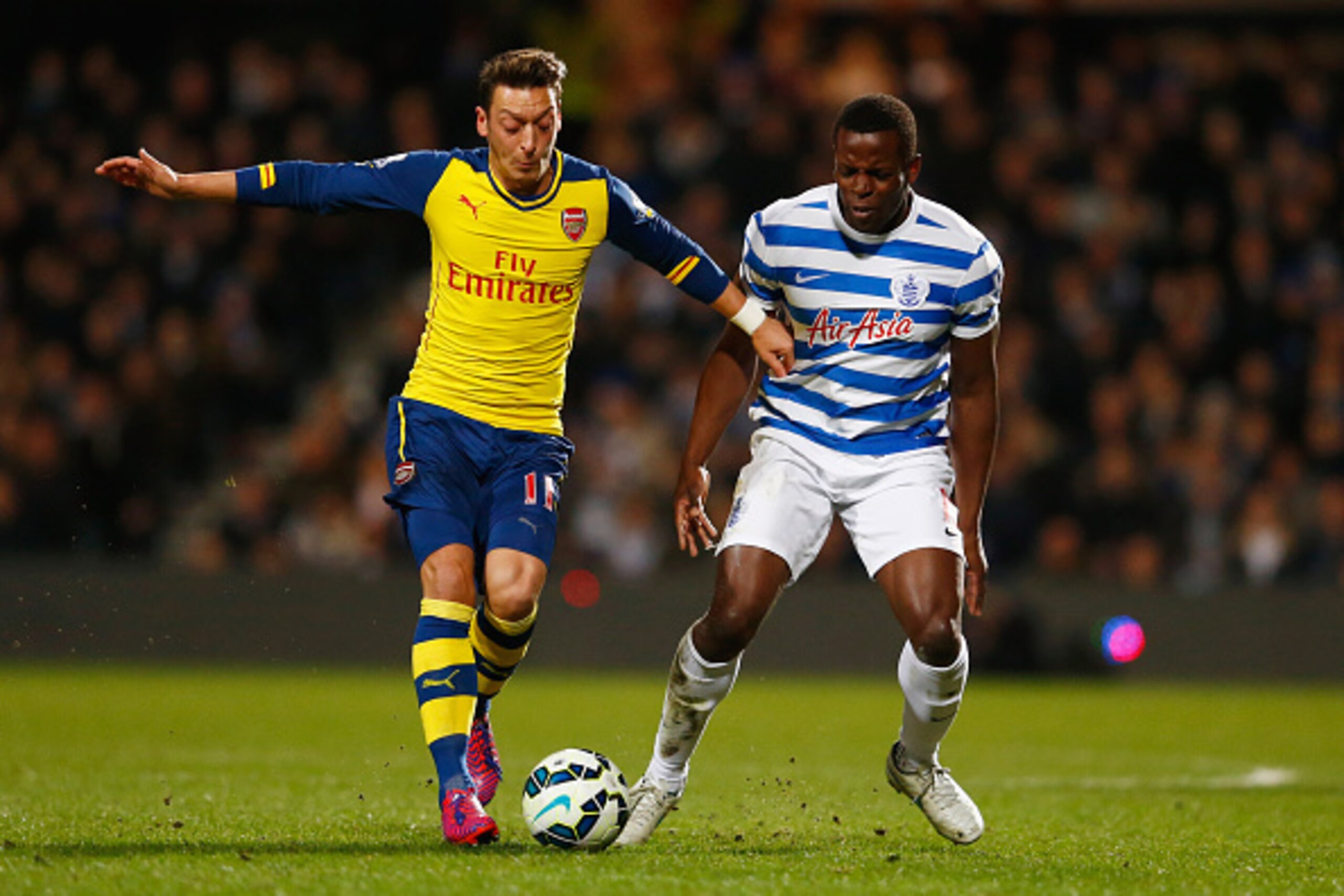 LONDON, ENGLAND - MARCH 04:  Mesut Oezil of Arsenal battles with Nedum Onuoha of QPR during the Barclays Premier League match between Queens Park Rangers and Arsenal at Loftus Road on March 4, 2015 in London, England.  (Photo by Julian Finney/Getty Images