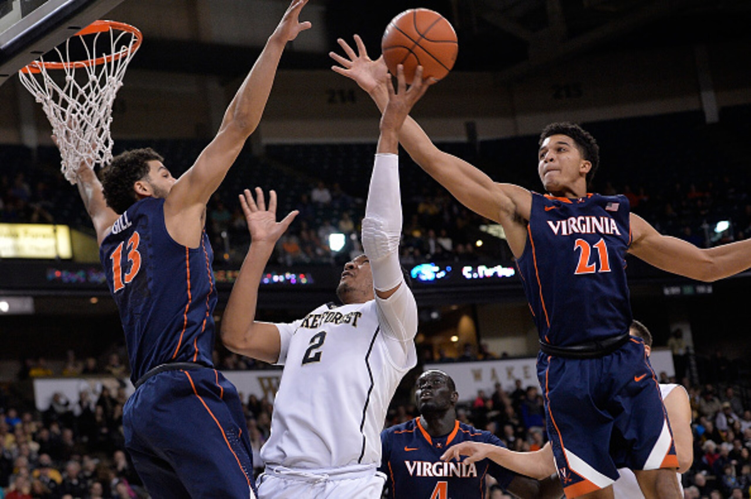 WINSTON-SALEM, NC - FEBRUARY 25:  Devin Thomas #2 of the Wake Forest Demon Deacons drives between Anthony Gill #13 and Isaiah Wilkins #21 of the Virginia Cavaliers during their game at the LJVM Coliseum Complex on February 25, 2015 in Winston-Salem, North