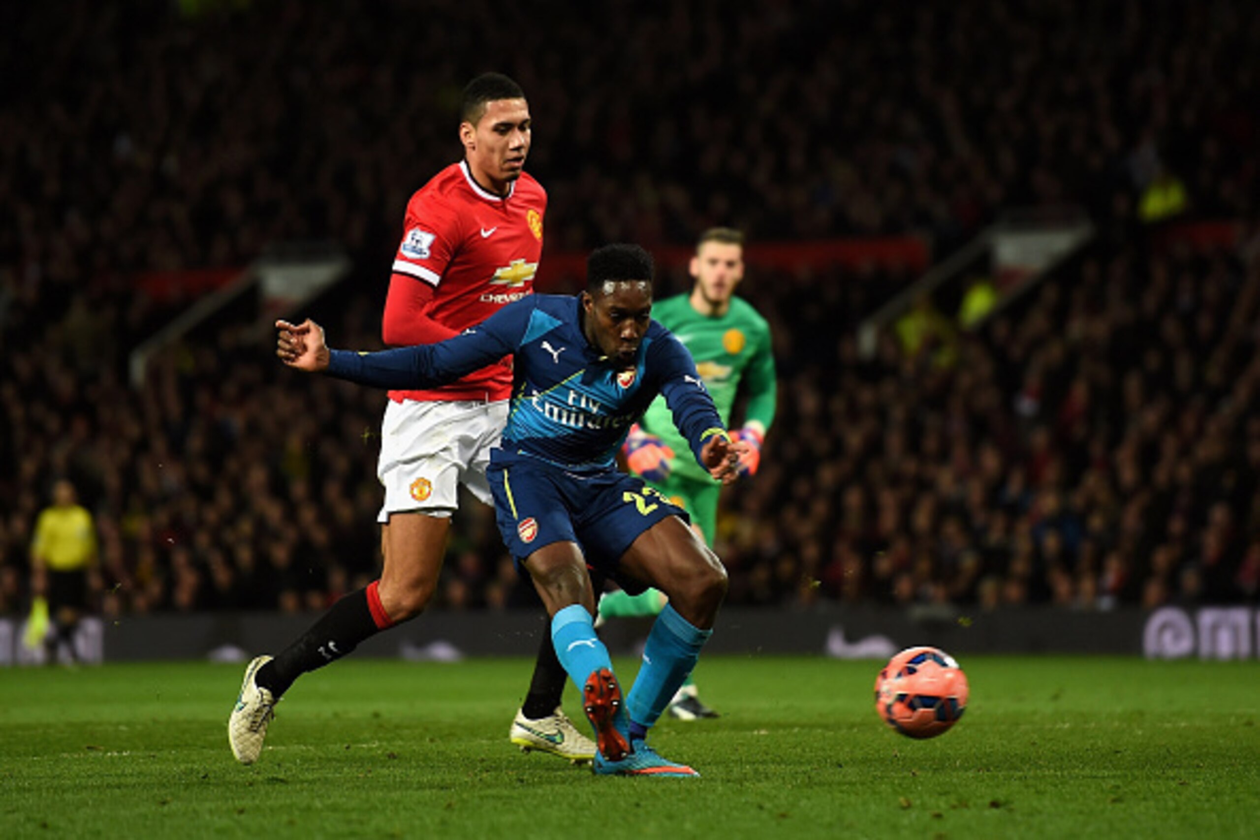 MANCHESTER, ENGLAND - MARCH 09:  Danny Welbeck of Arsenal scores his team's second goal despite the attentions from Chris Smalling of Manchester United during the FA Cup Quarter Final match between Manchester United and Arsenal at Old Trafford on March 9,