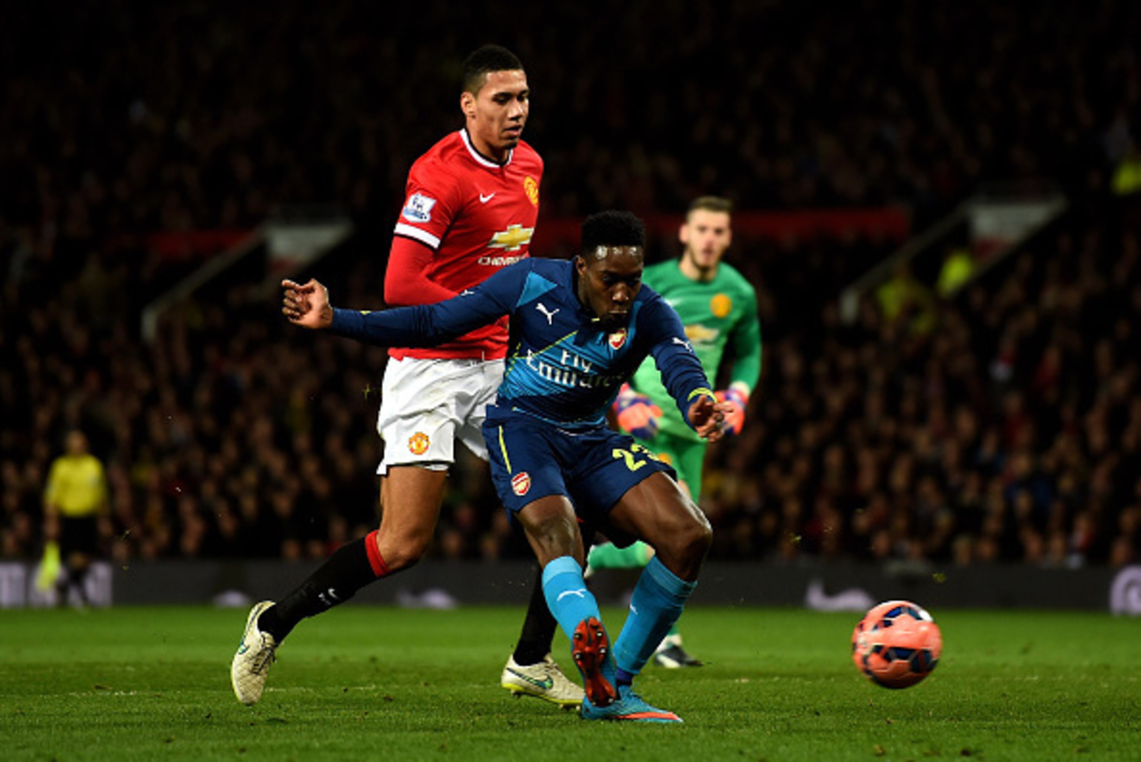 MANCHESTER, ENGLAND - MARCH 09:  Danny Welbeck of Arsenal scores his team's second goal despite the attentions from Chris Smalling of Manchester United during the FA Cup Quarter Final match between Manchester United and Arsenal at Old Trafford on March 9,