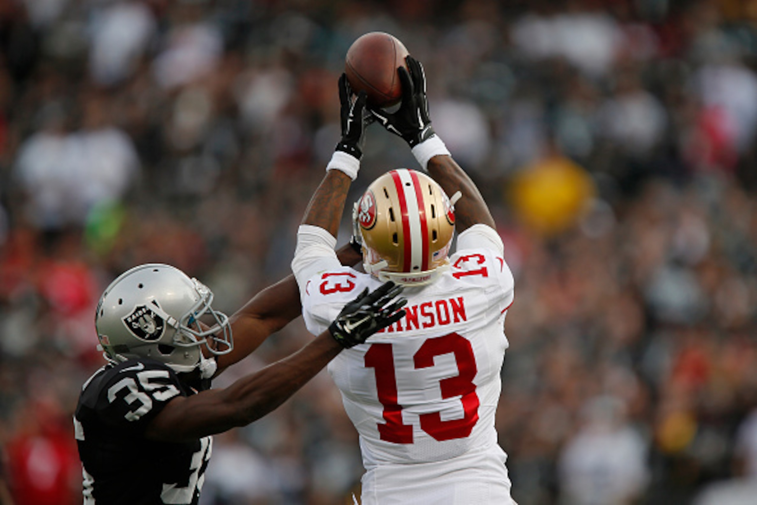 OAKLAND, CA - DECEMBER 7:  Wide receiver Stevie Johnson #13 of the San Francisco 49ers tries unsuccessfully to pull down a pass against cornerback Chimdi Chekwa #35 of the Oakland Raiders in the second quarter on December 7, 2014 at O.co Coliseum in Oakla