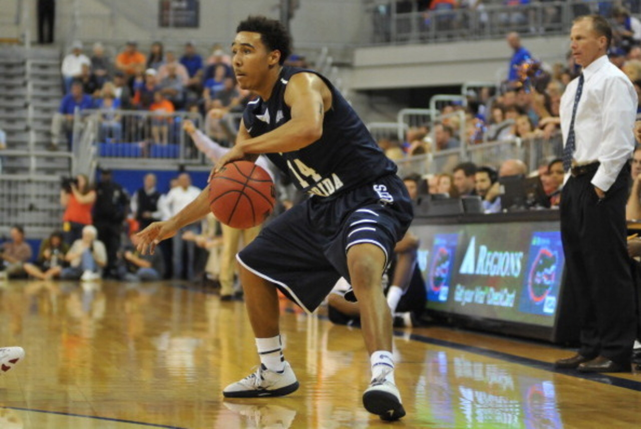 GAINESVILLE, FL - NOVEMBER 8:  Guard Dallas Moore #14 of the North Florida Ospreys drives up court against theFlorida Gators  November 8, 2013 at the Stephen C. O'Connell Center in Gainesville, Florida. (Photo by Al Messerschmidt/Getty Images)